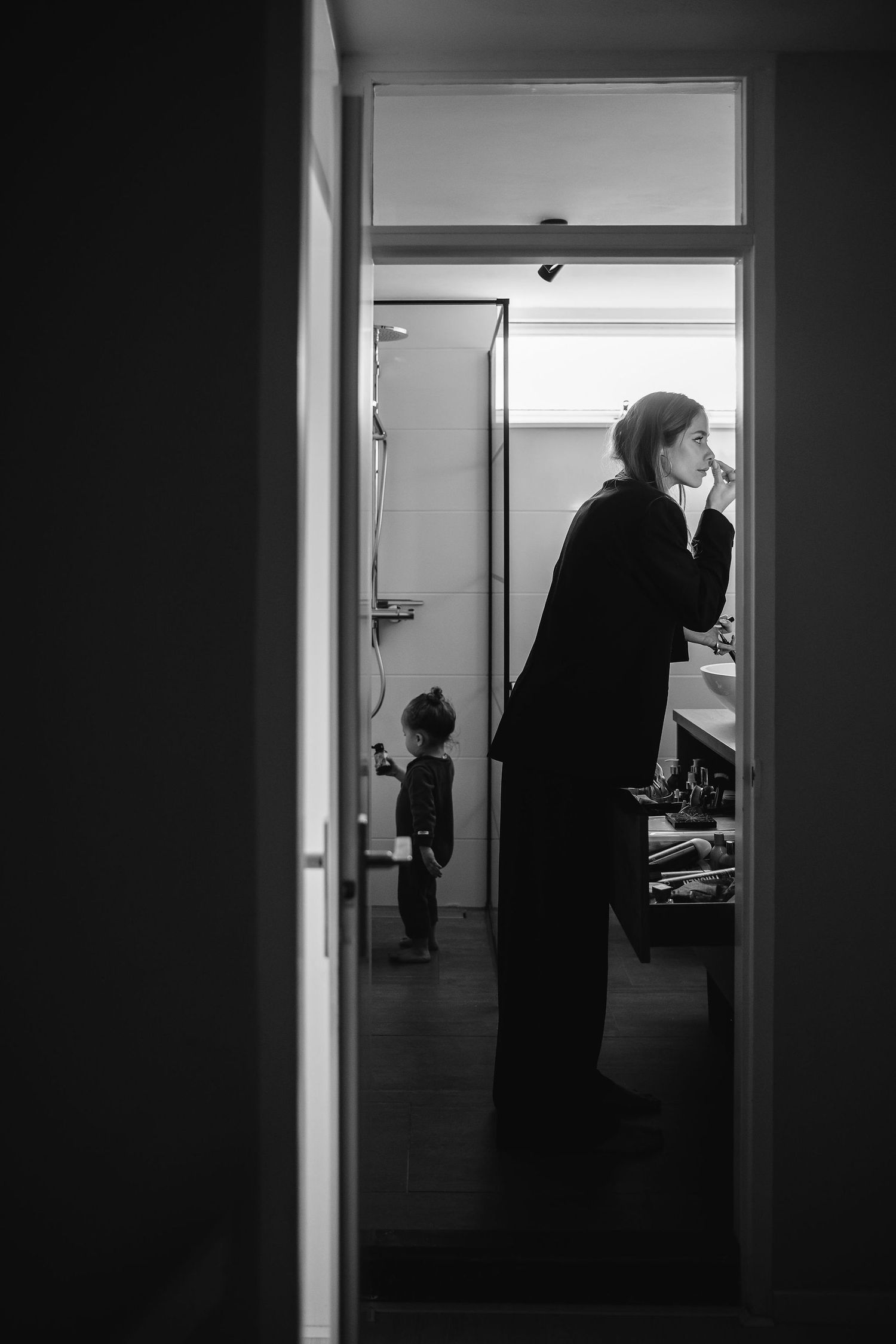 Moody black and white silhouettes through doorway showing intimate daily moments.