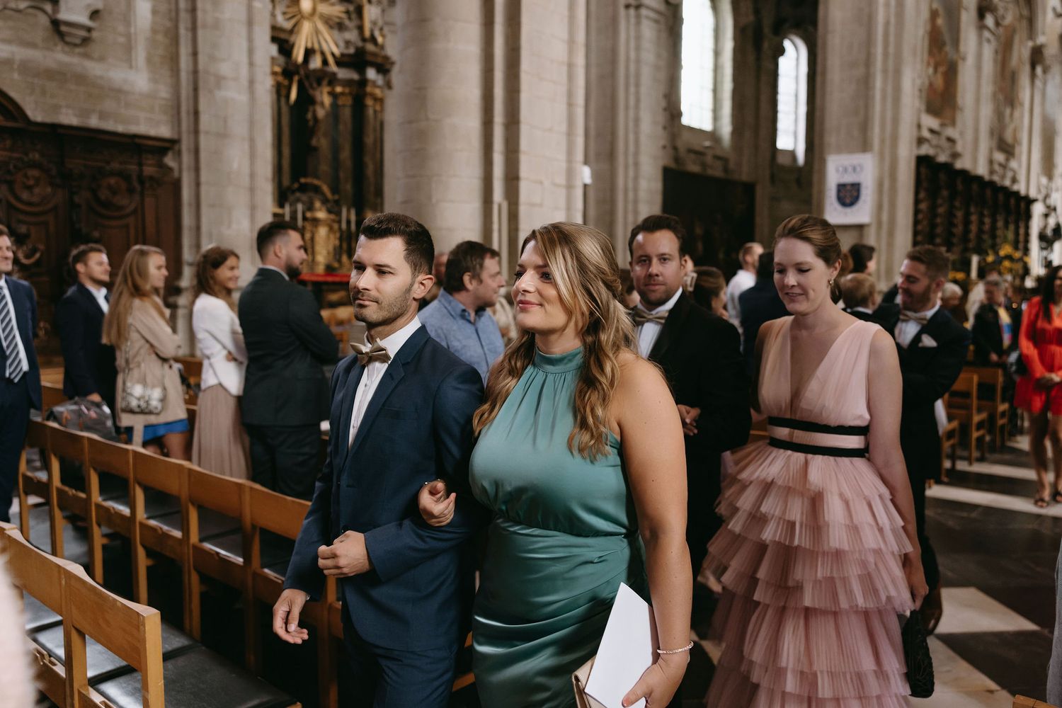 Wedding guests seated in ornate church pews during ceremony.