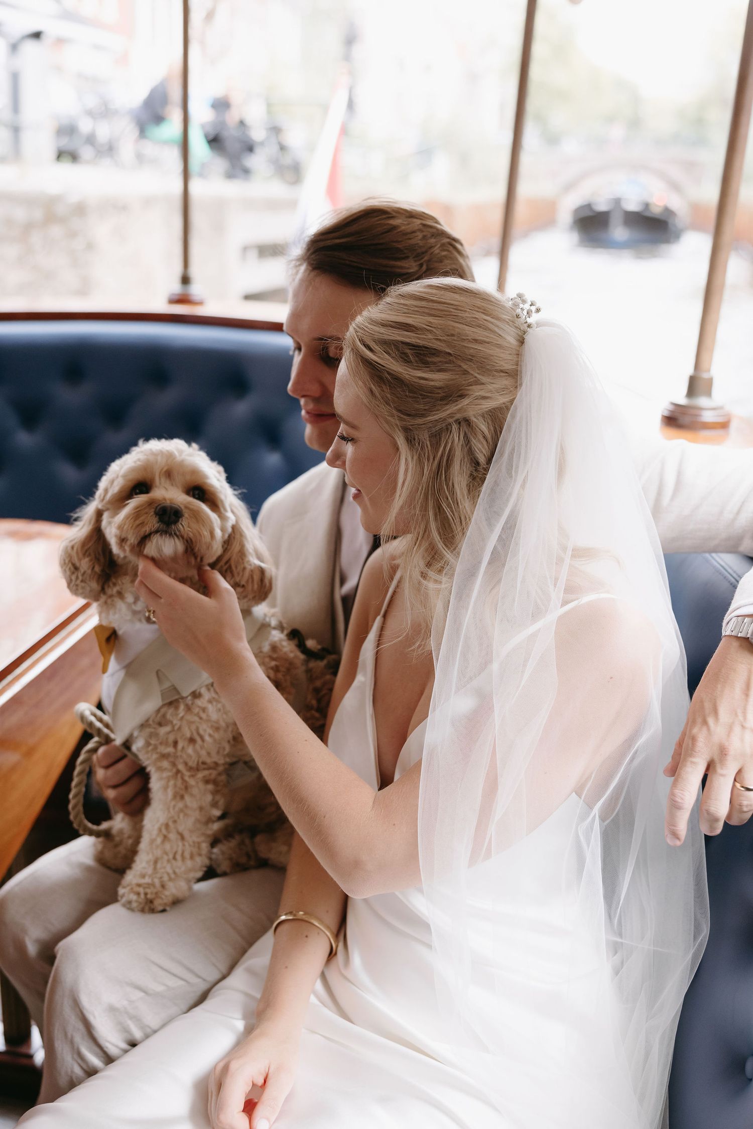 Wedding couple cuddles with their small dog on boat ride.