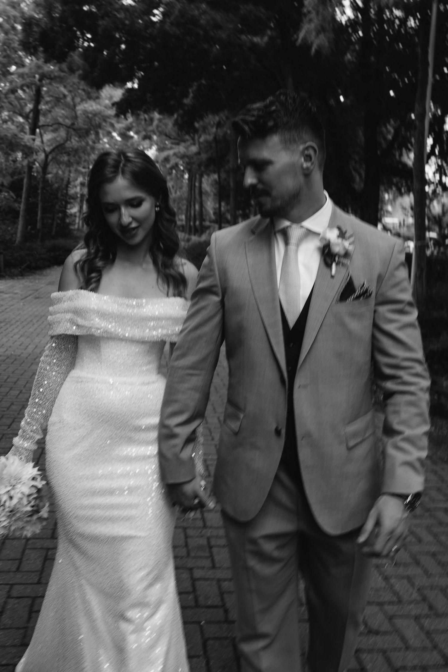 Wedding party in gray suits and white dress posing outdoors on brick pavement.