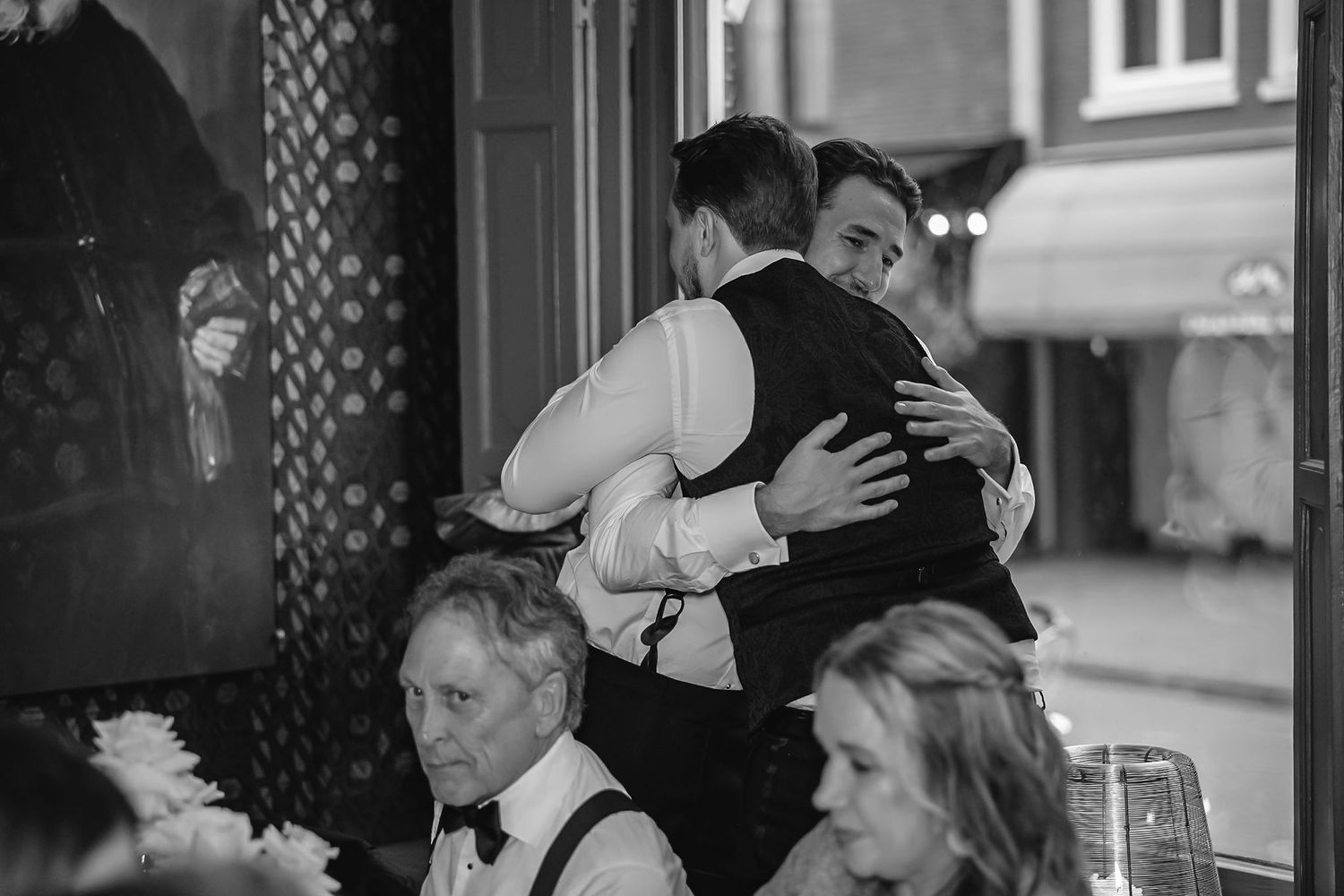 Black and white candid moments from an indoor wedding reception.
