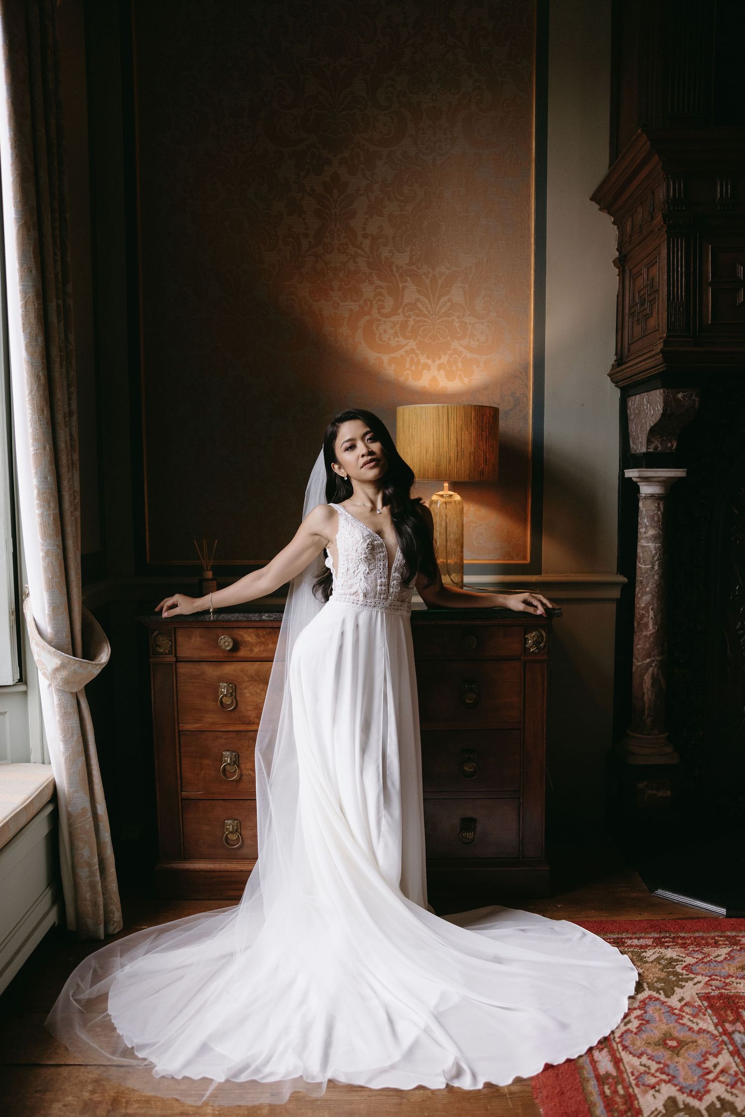 Elegant wedding dress with flowing train displayed dramatically across a luxurious bedroom floor.