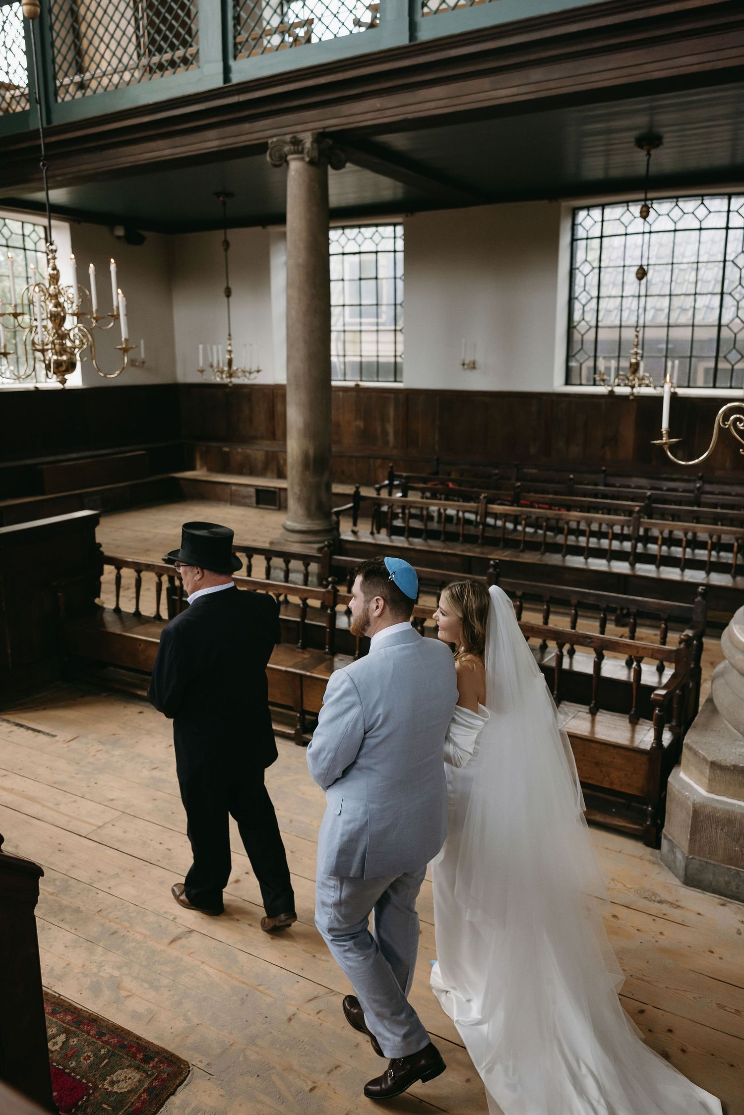 Interior of historic synagogue with wooden pews and traditional architecture during ceremony.
