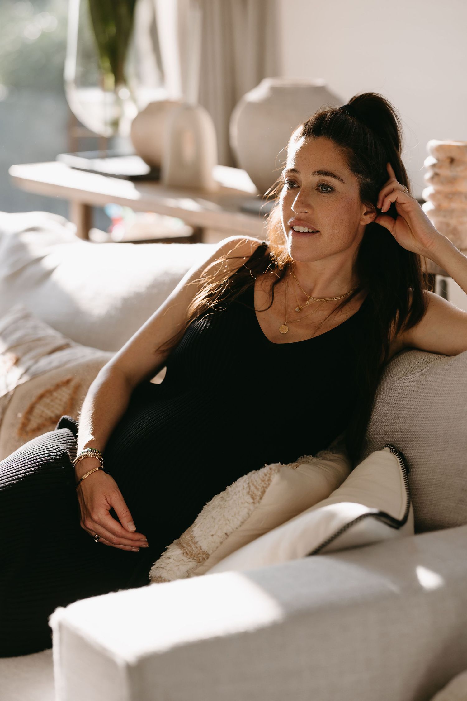 Lifestyle portrait of woman relaxing on couch in sunlit living room.