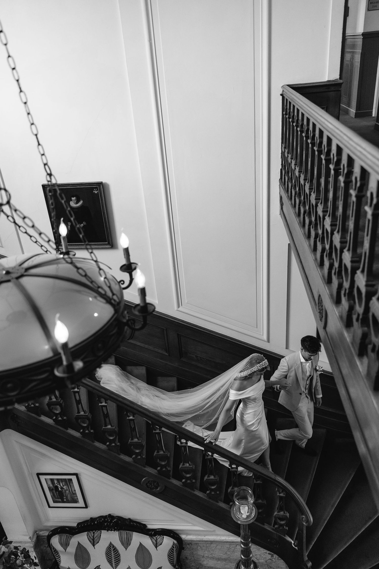 Black and white photos of an elegant staircase with white walls and dark railings.