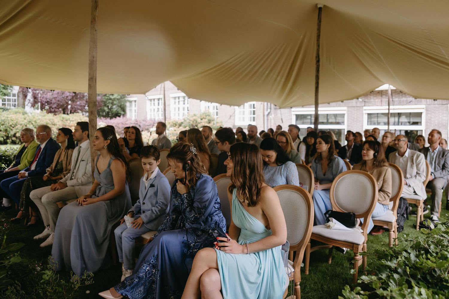 An outdoor wedding ceremony setup under a white tent with blue decor accents.