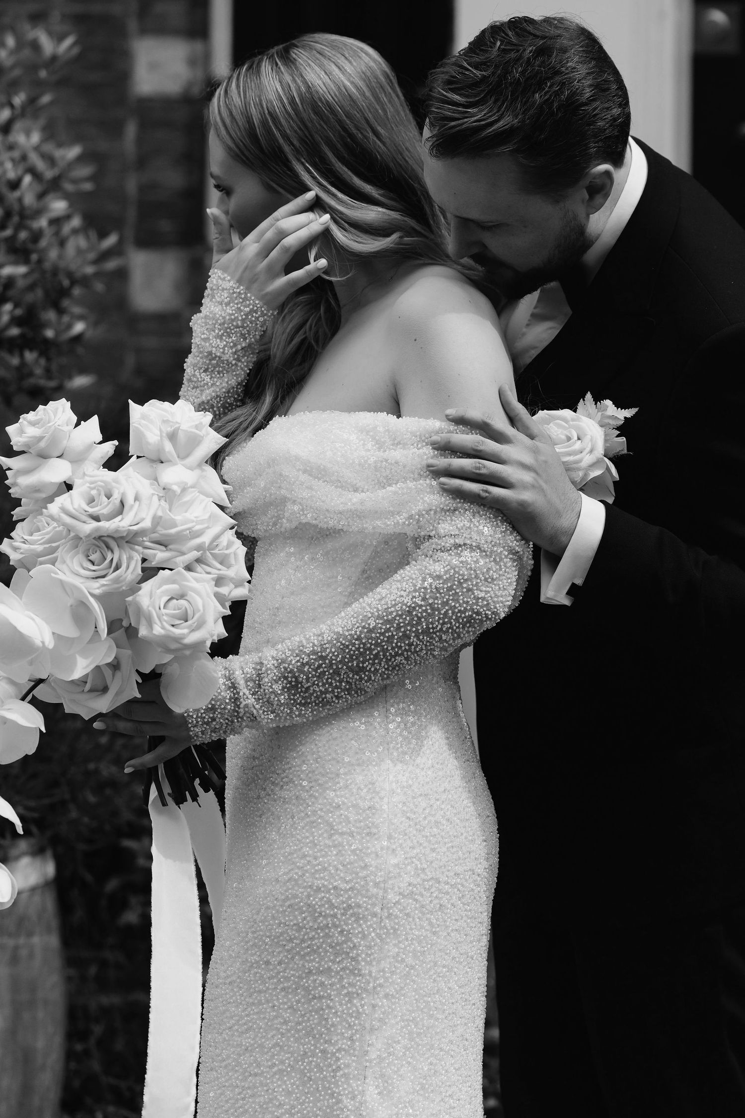 Intimate black and white moment between couple with white roses bouquet.