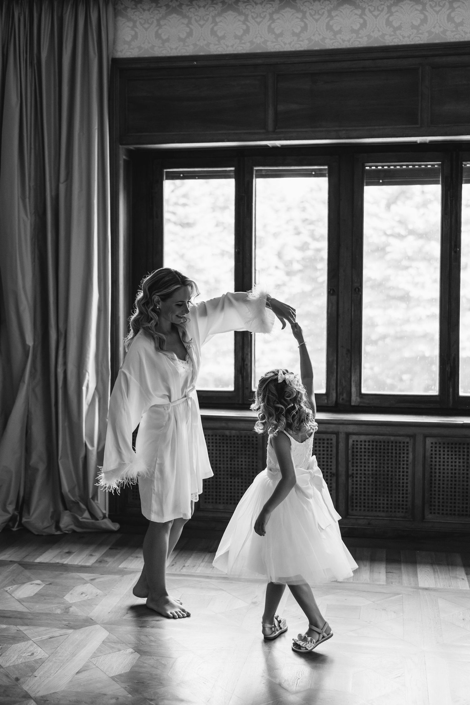 Sweet moment of dancing in a sunlit room with hardwood floors.