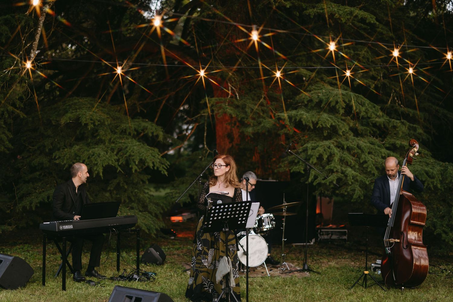 Musicians performing at an outdoor evening wedding reception with string instruments.