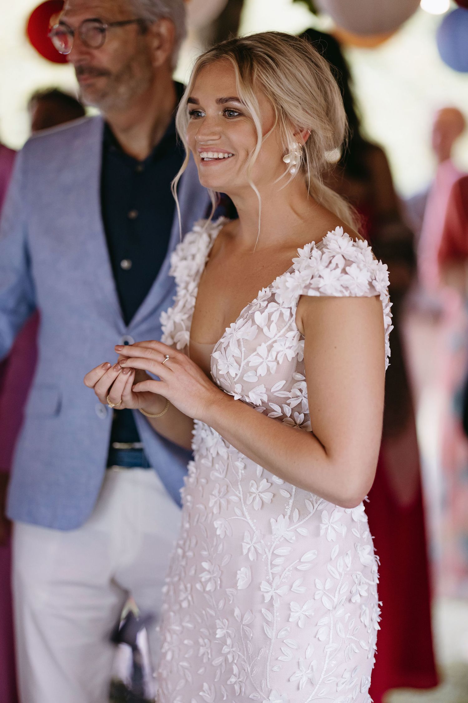 Wedding reception dance with guests in formal attire under decorated tent.