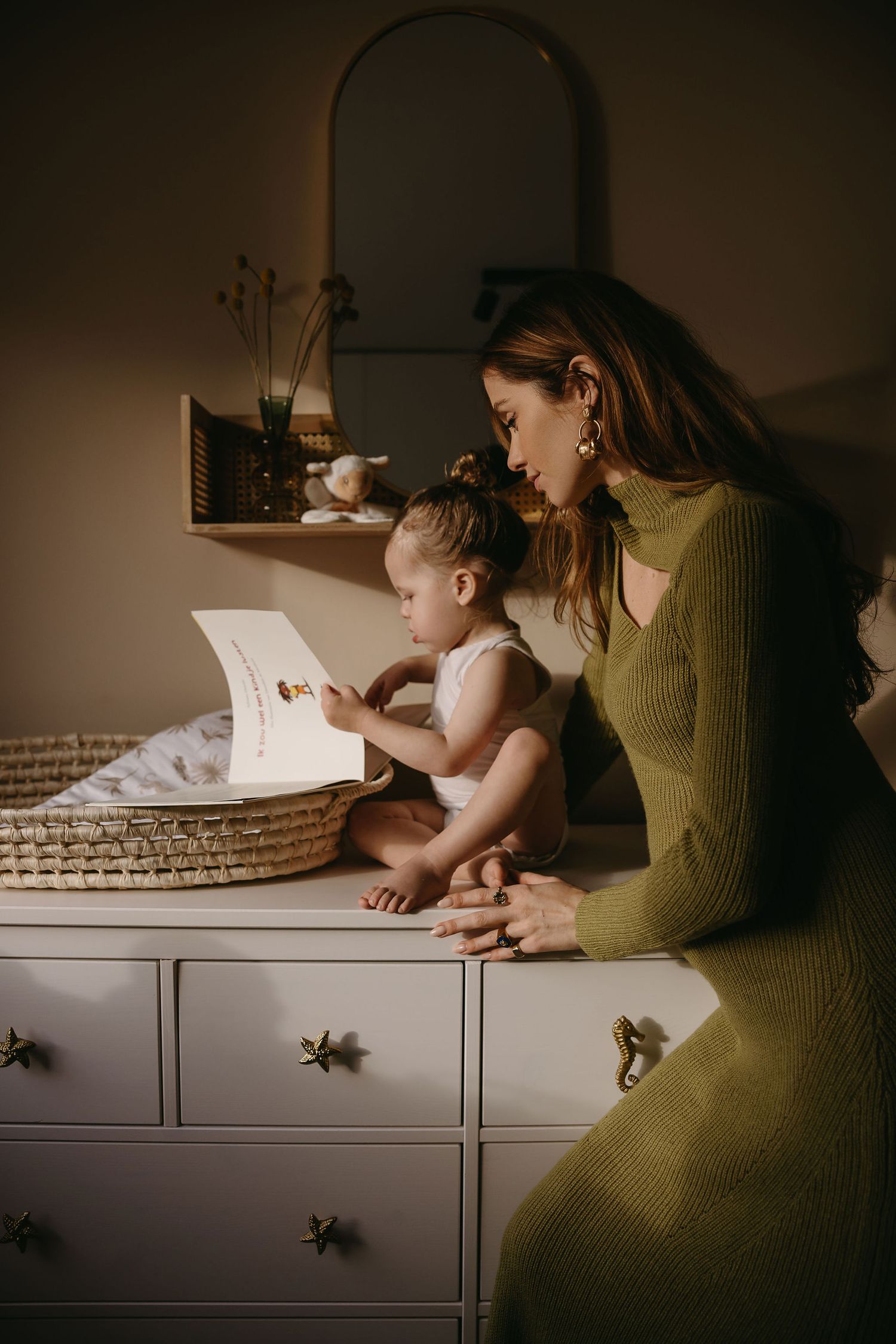 A cozy scene of reading together on a dresser with a lamp and basket in warm lighting.