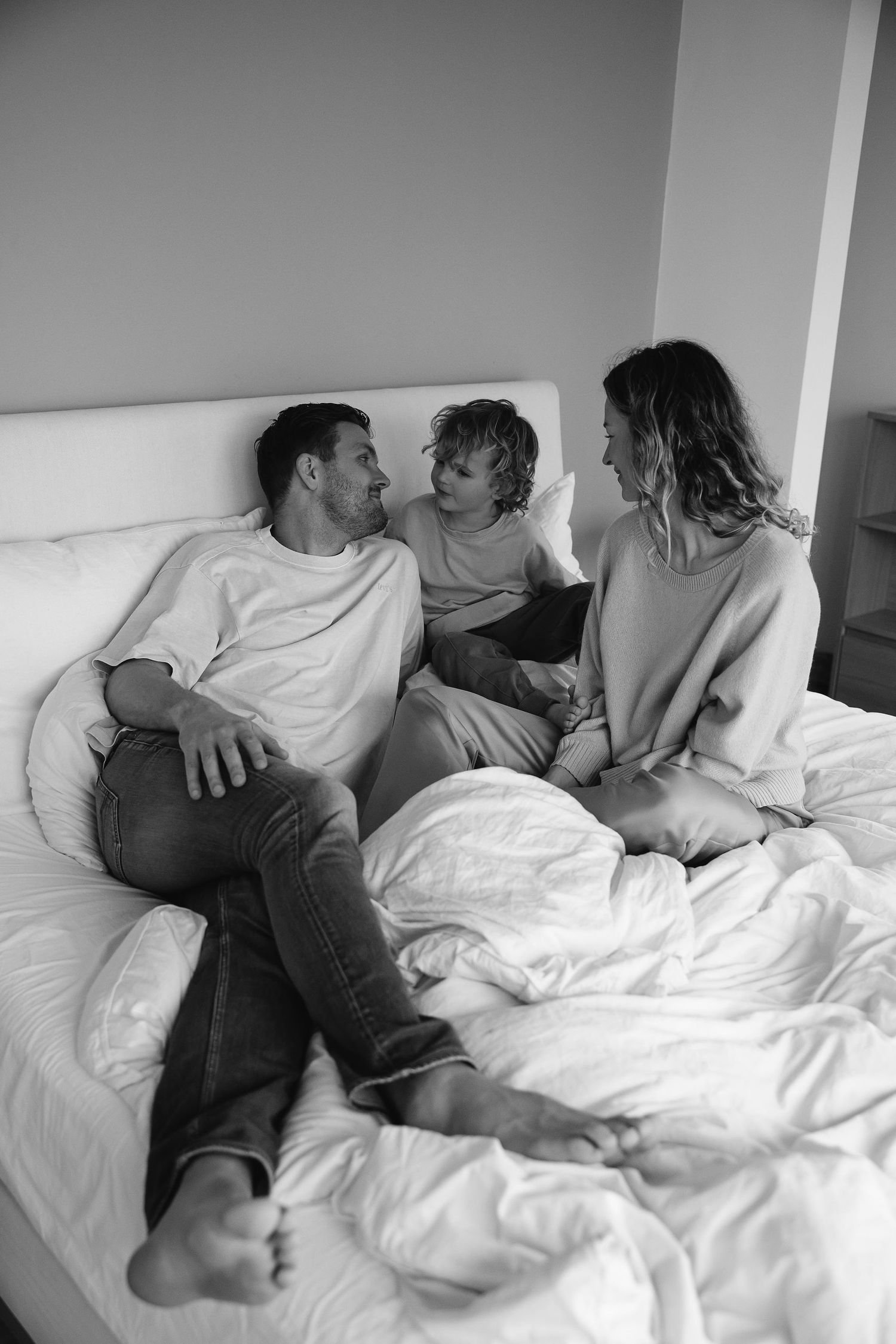 Family sharing intimate moment together on white couch in black and white.