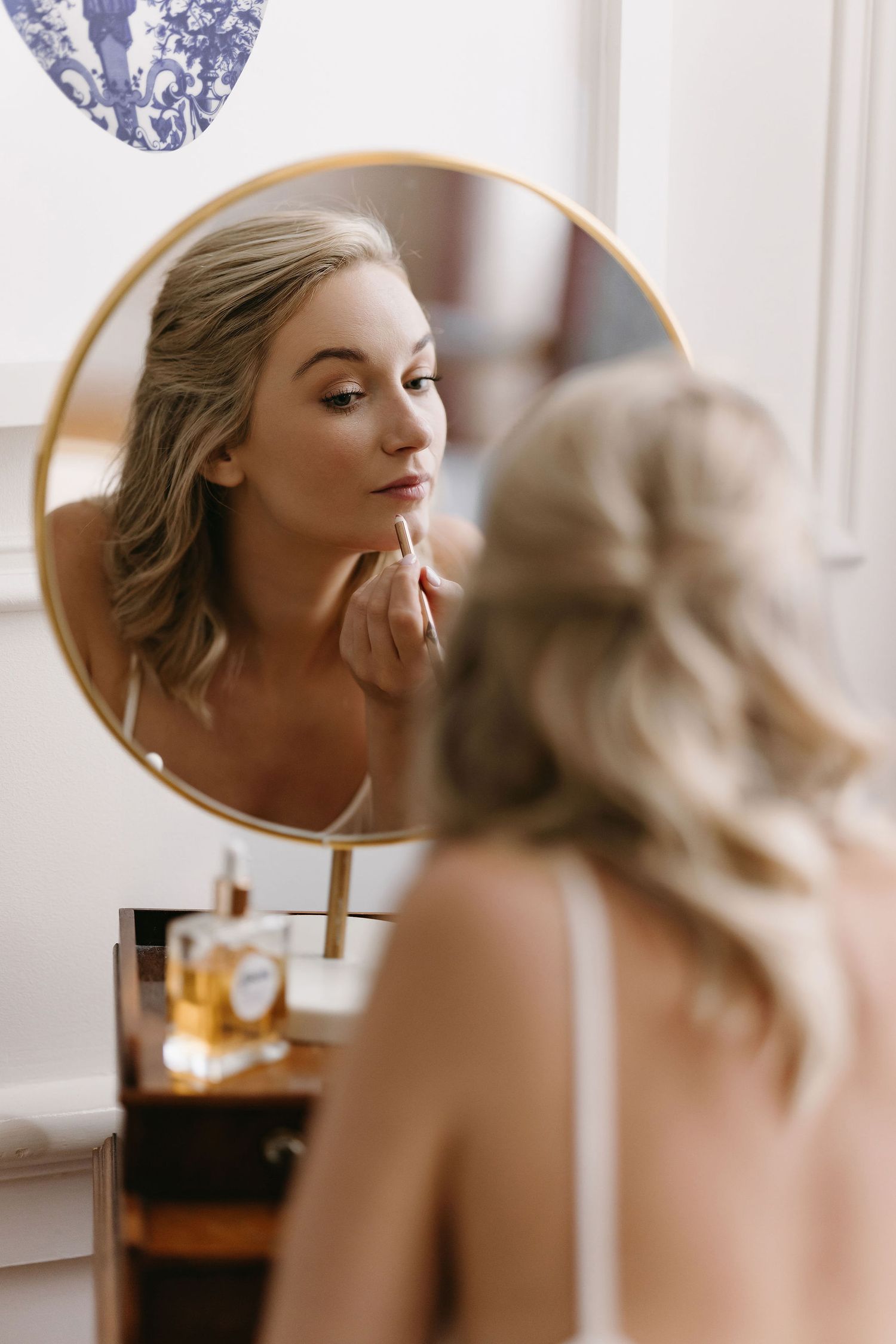 Reflection of a woman applying makeup in an elegant vintage-style vanity mirror.