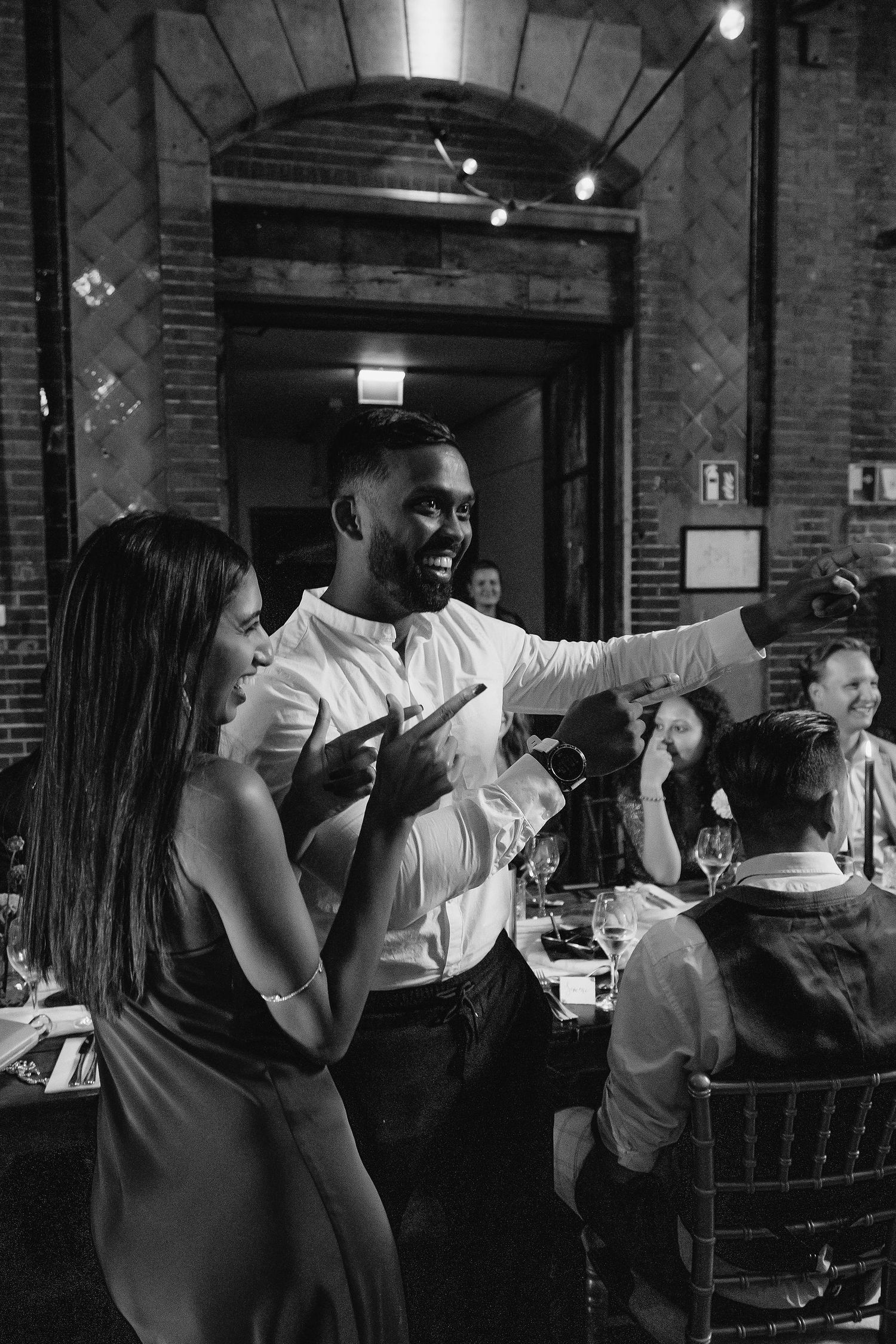 Wedding reception guests dancing and celebrating in dimly lit brick venue.