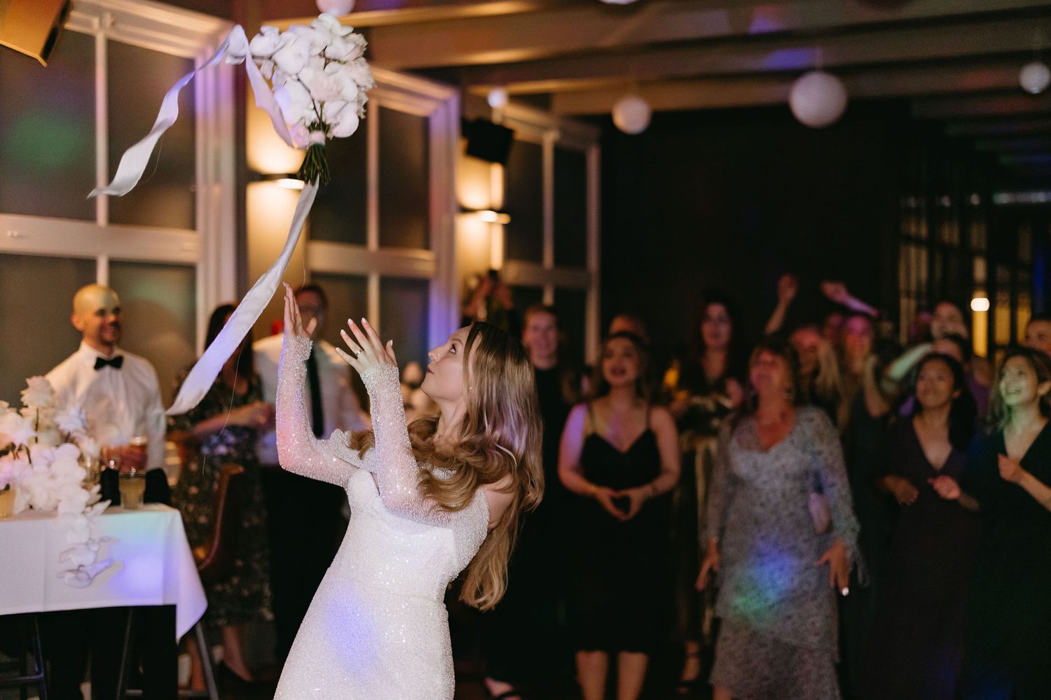 Wedding reception scene showing dancers celebrating under decorative ceiling lighting.