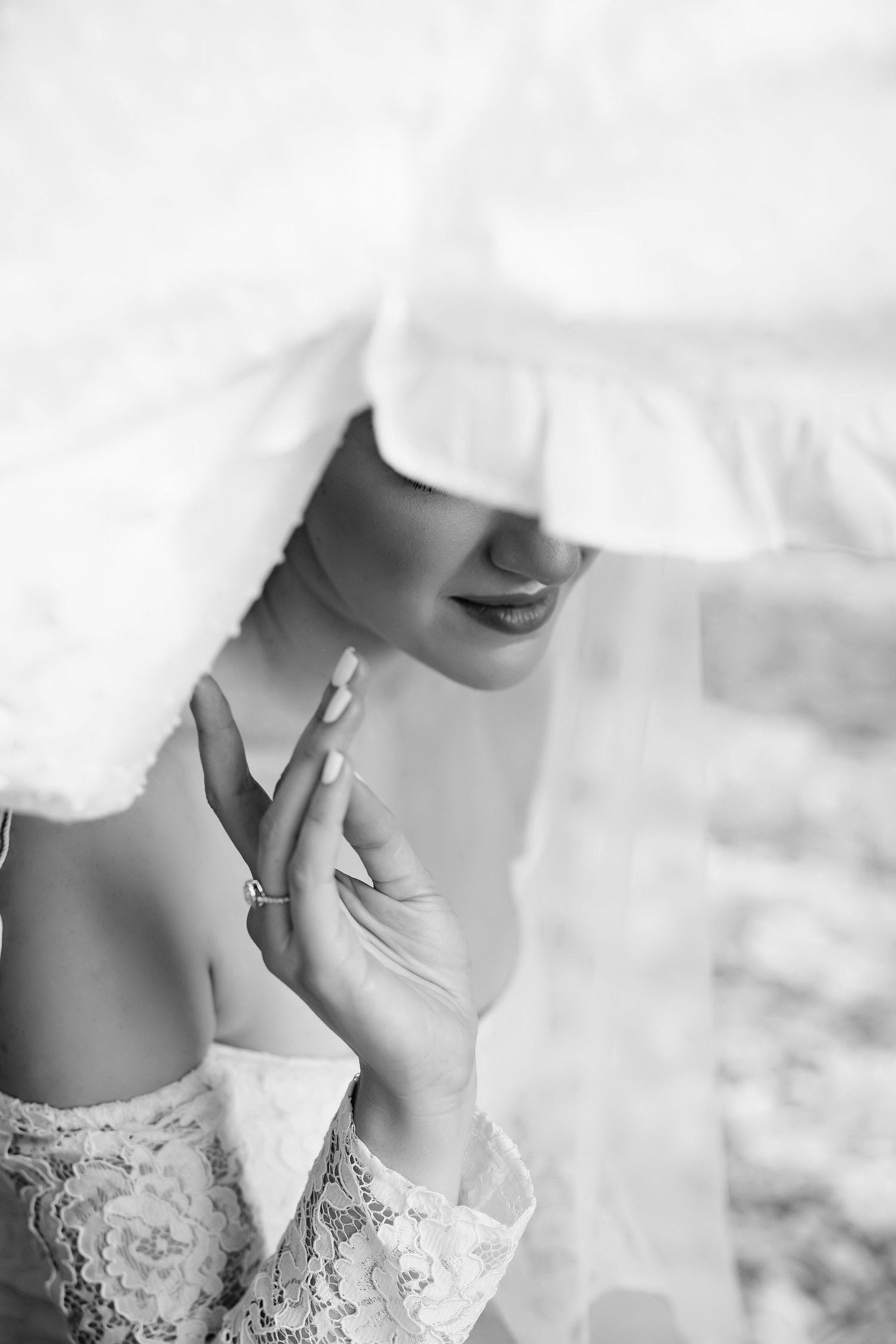 Close-up black and white image showing intricate lace details of a bridal dress design.