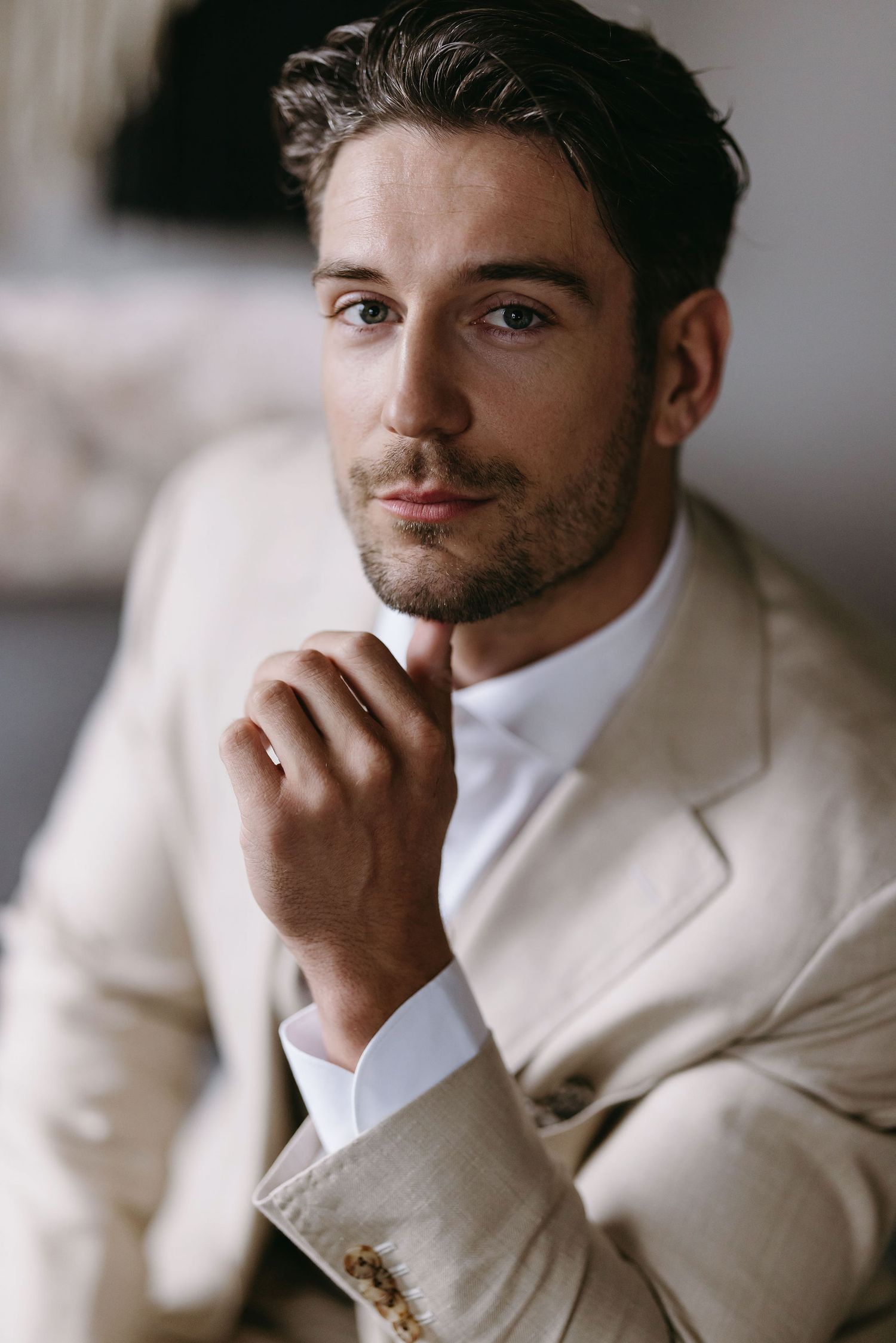 Portrait of person in cream colored suit jacket with thoughtful expression.