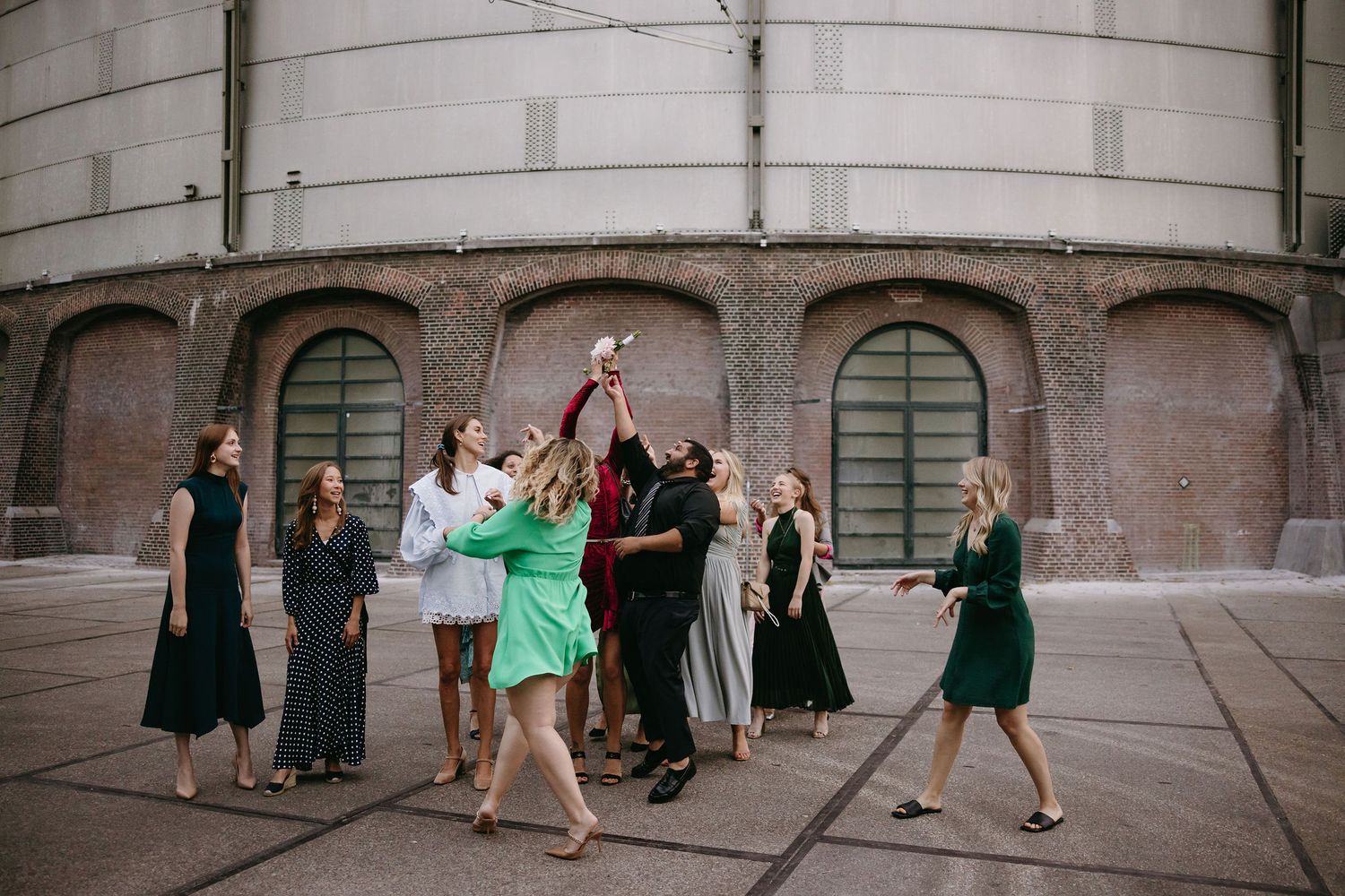 Wedding guests gather outside historic building for group celebration photos.