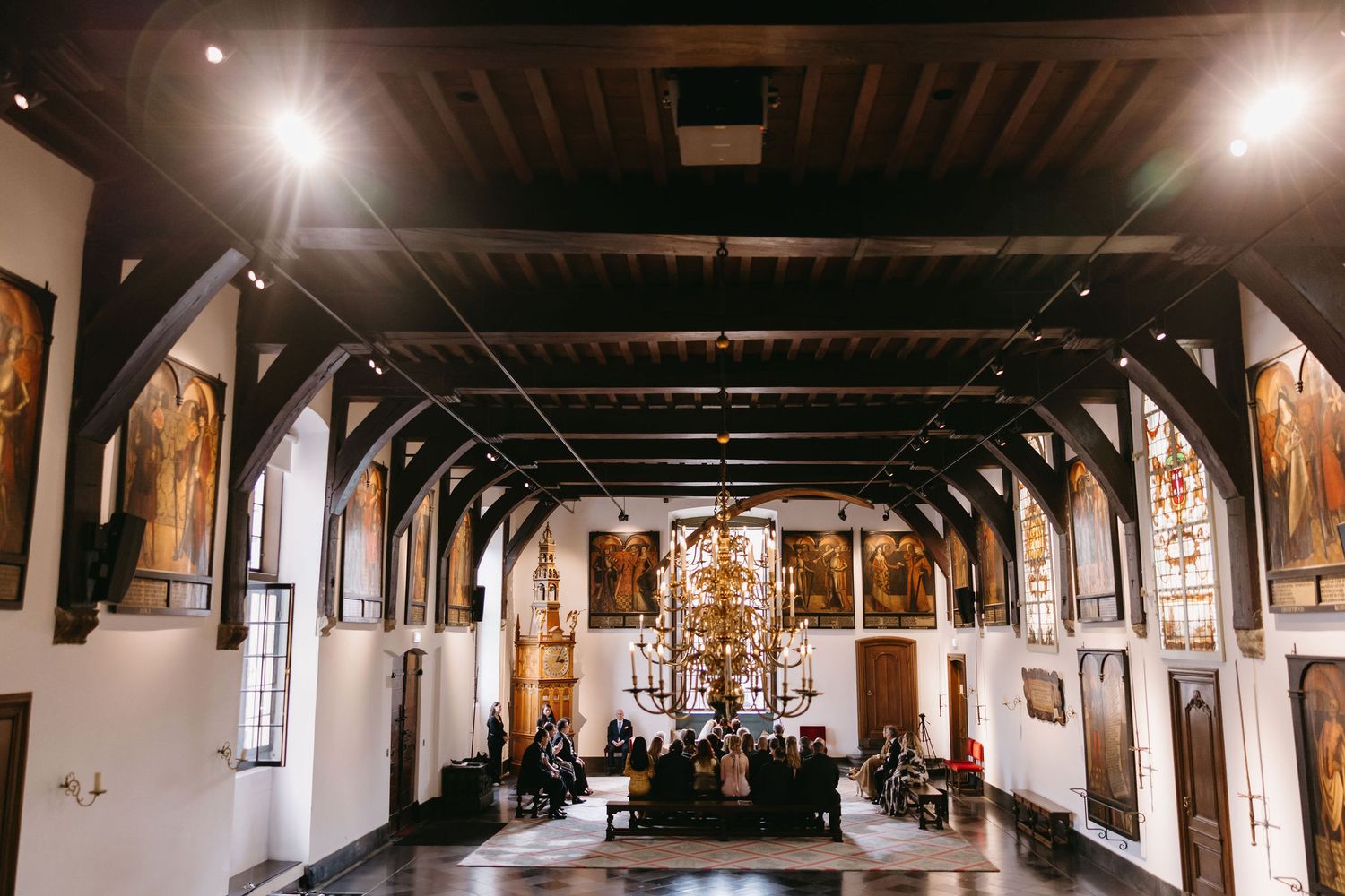 Wide panoramic view of a grand church interior with wooden beams and chandeliers.