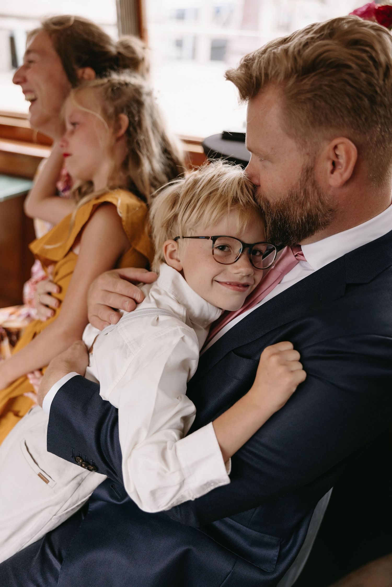 A touching candid family moment during a wedding celebration with formal attire and warm expressions.