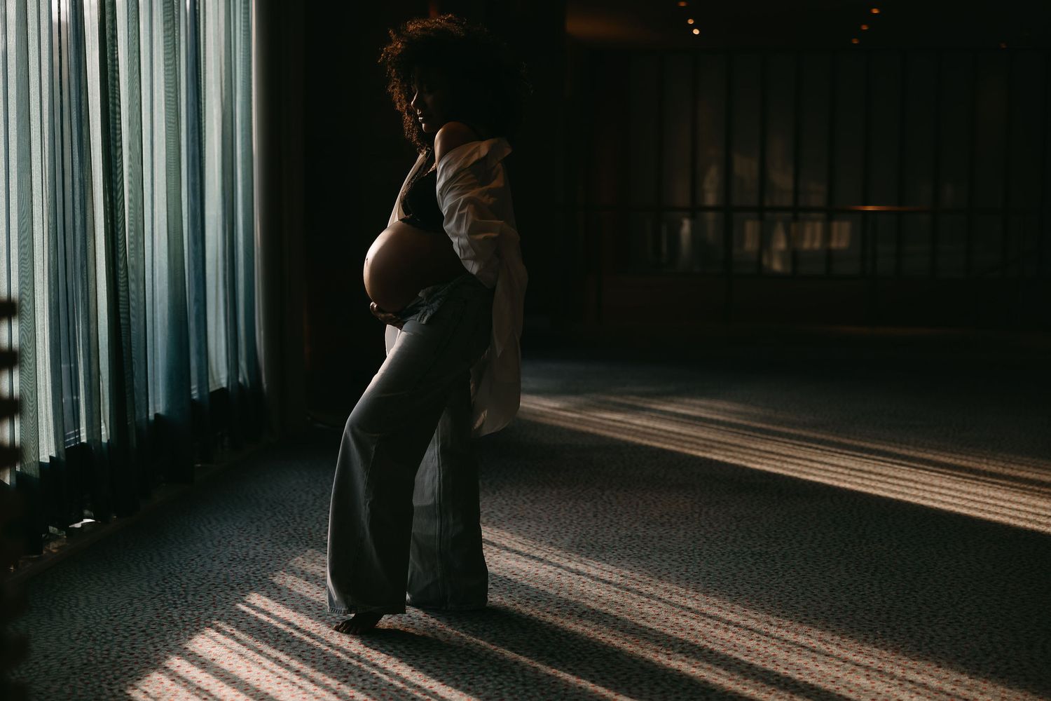 Natural light creates dramatic shadows through curtains in a minimal interior setting.