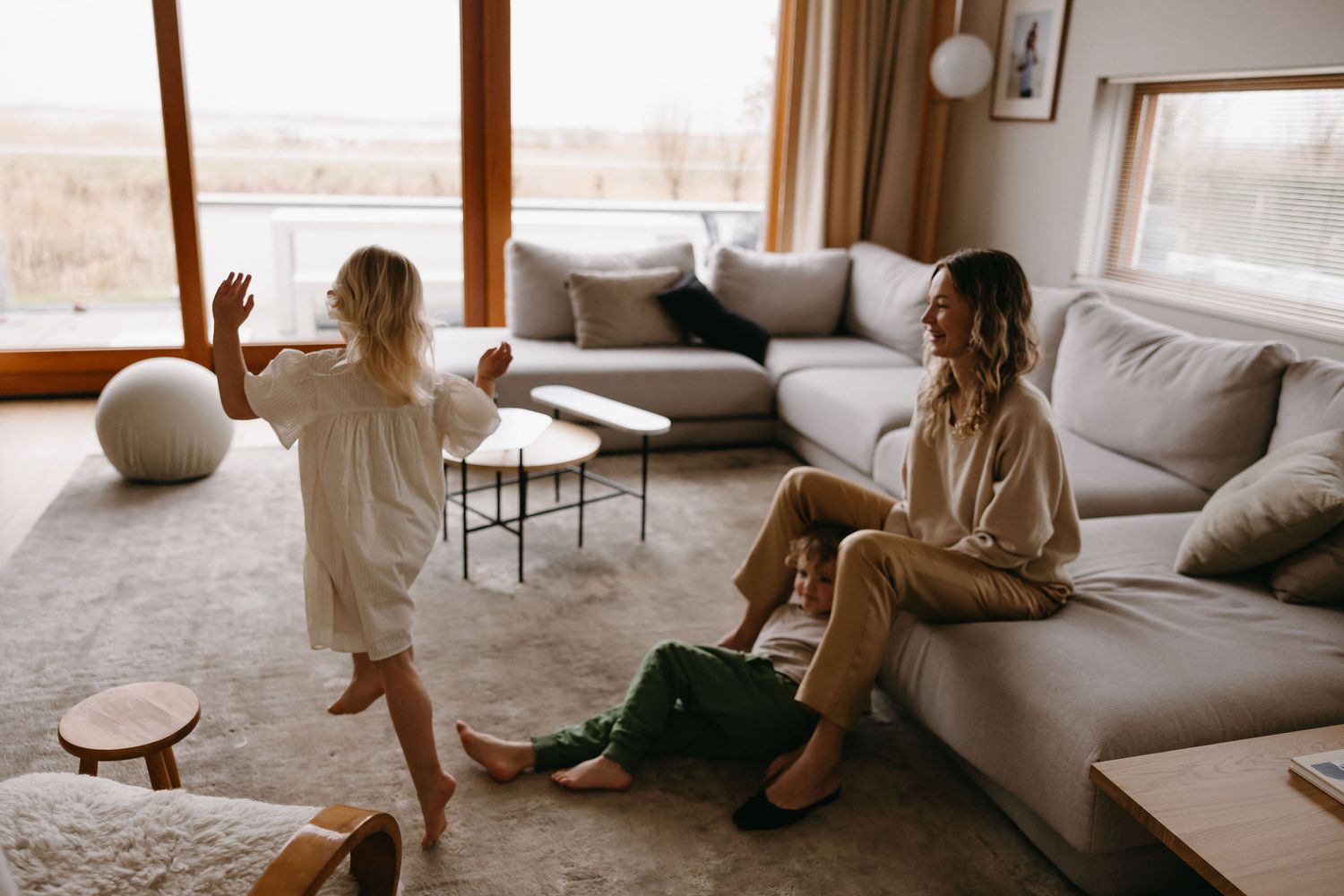 Candid moment of family bonding in modern living room with large windows.