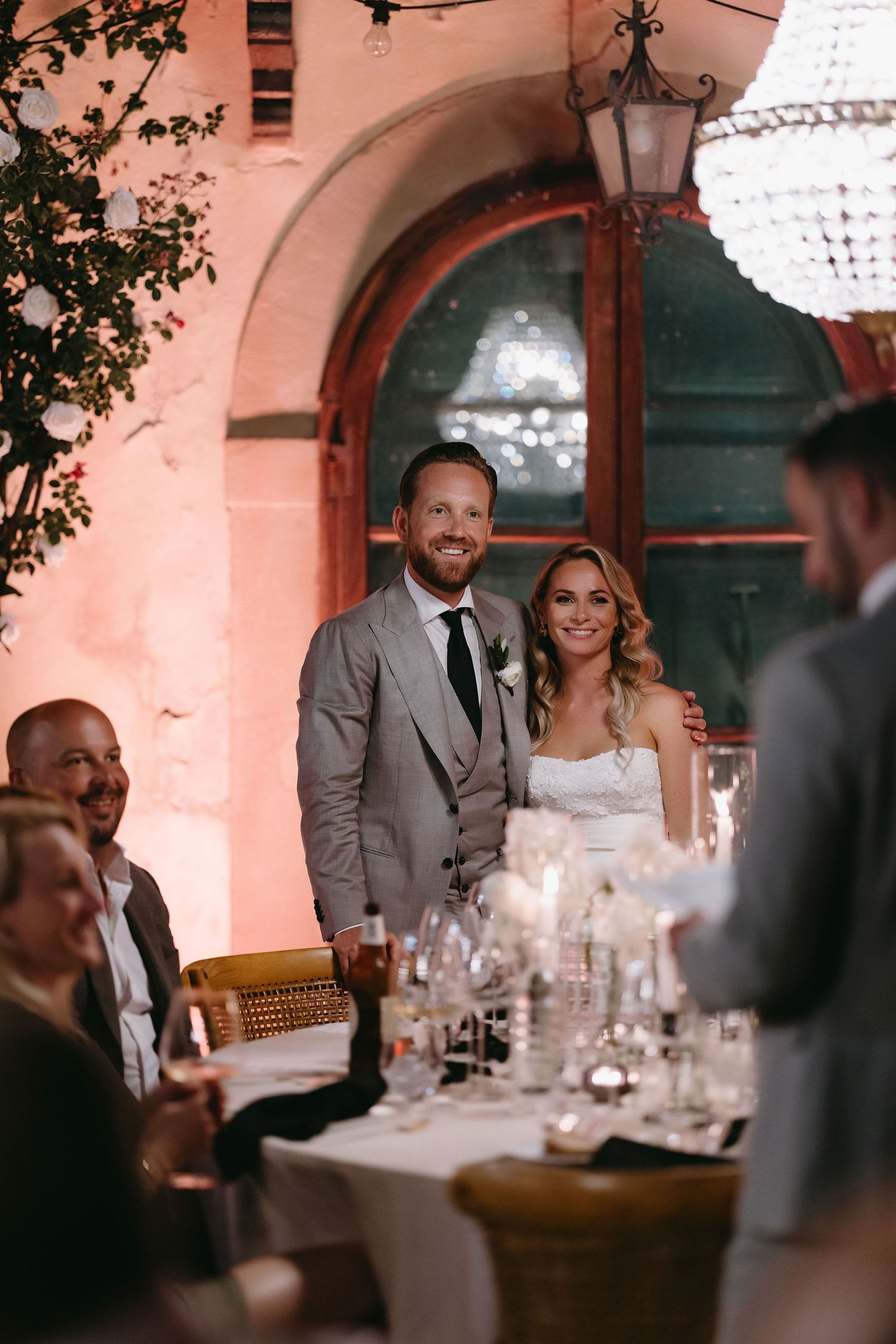Wedding reception dinner scene with elegant table settings and ambient lighting.