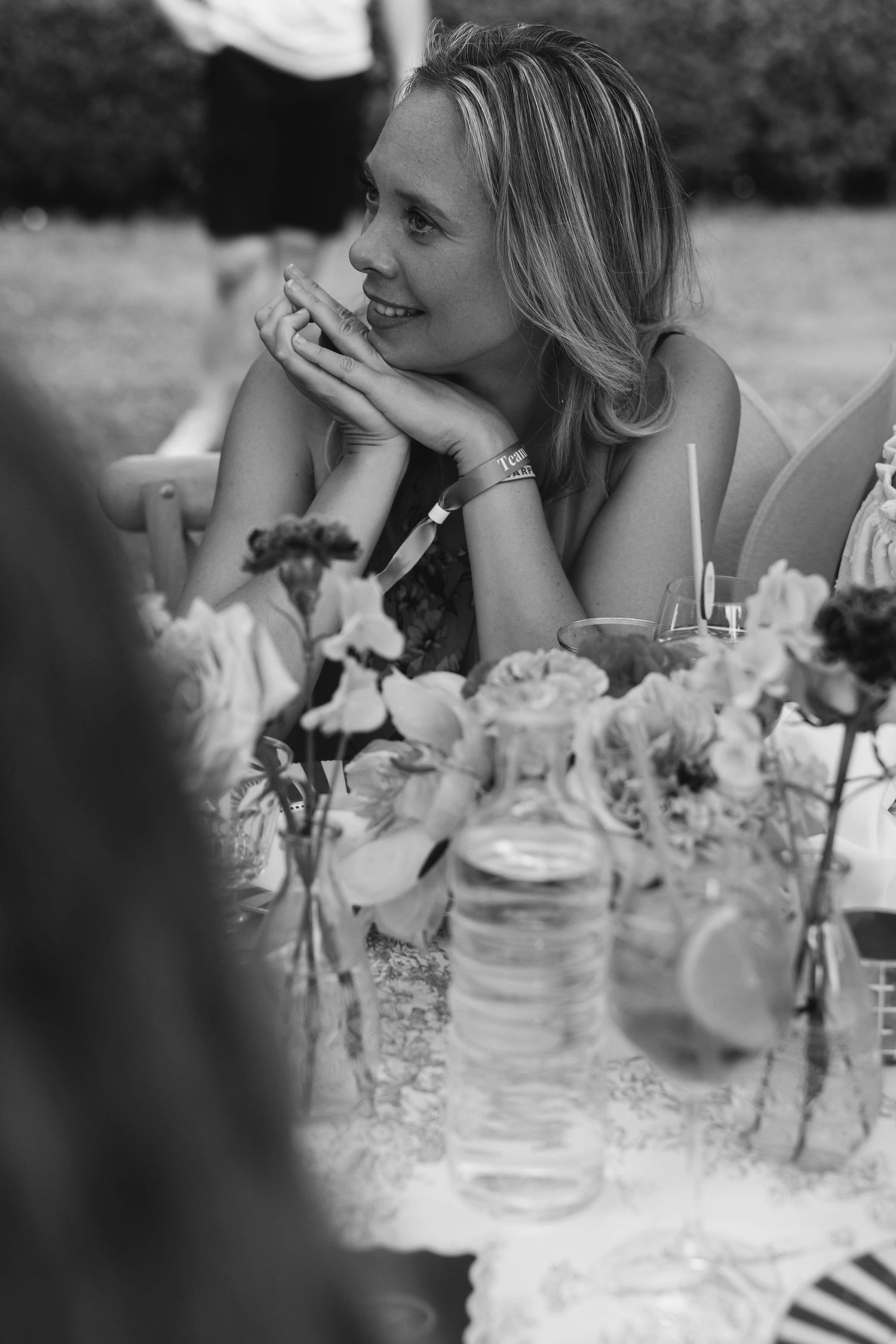 Black and white photograph of reception table with floral centerpieces and glassware.