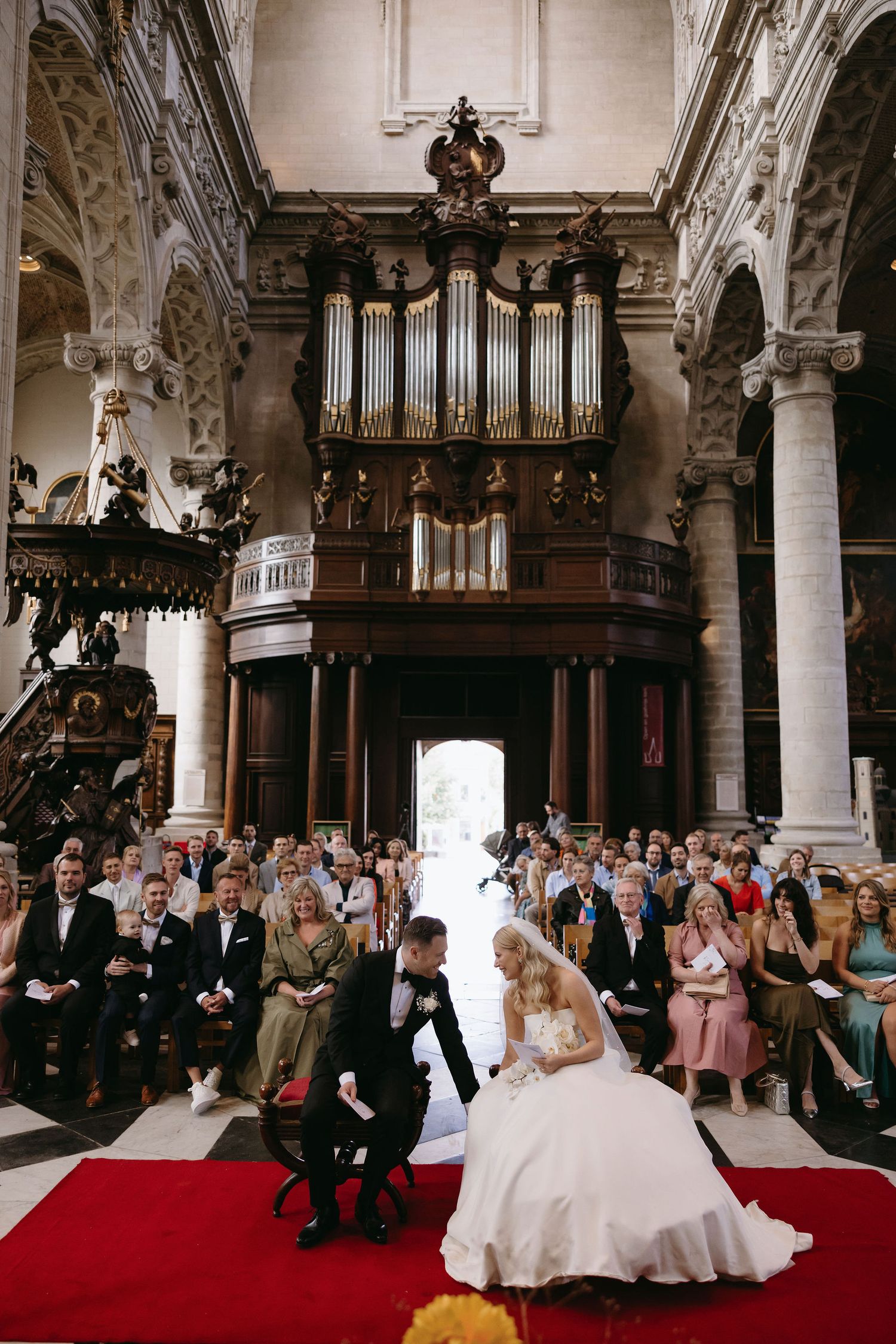 Grand church wedding ceremony with ornate organ pipes and architecture in the background.