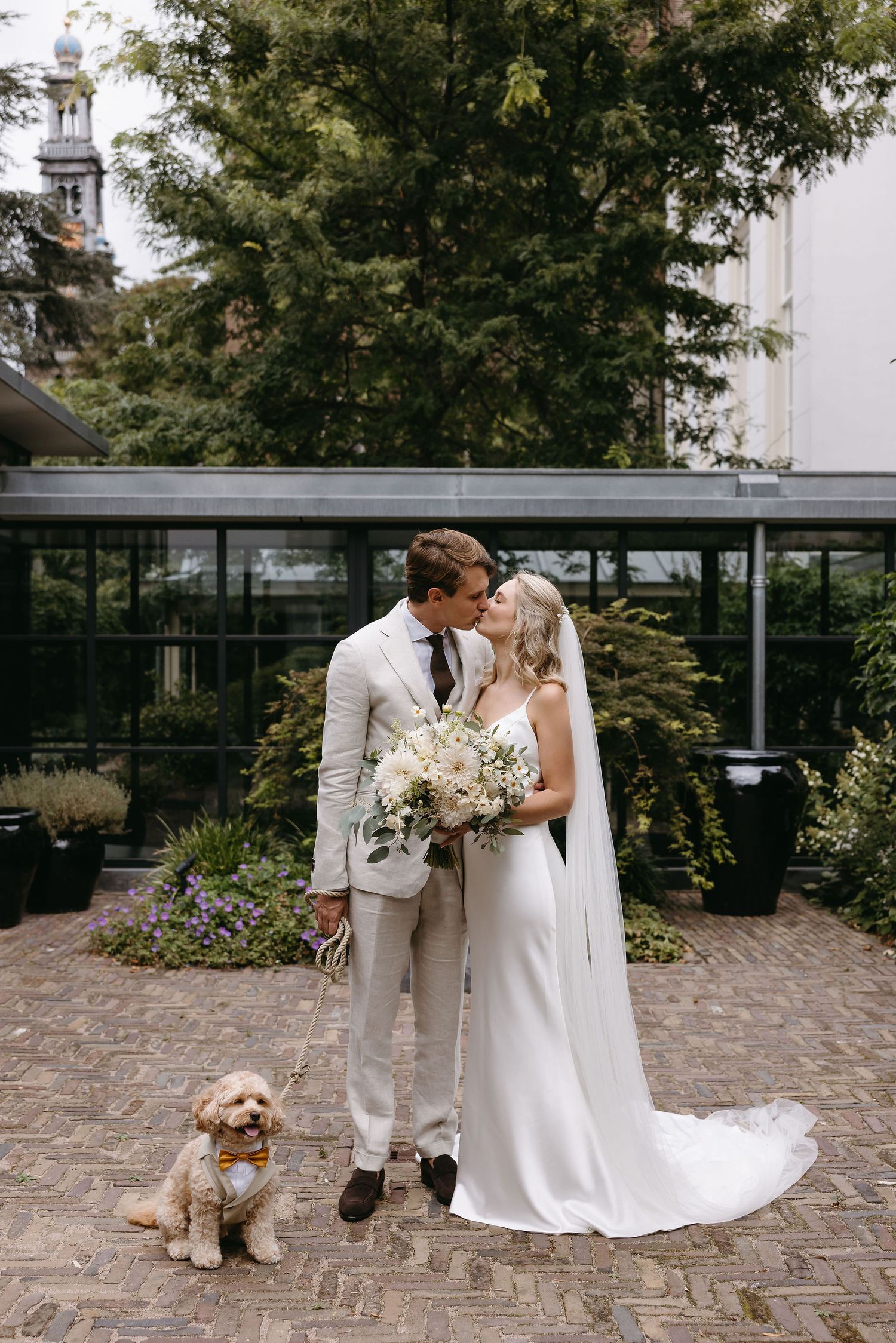 Wedding couple sharing intimate moment in garden setting with their goldendoodle dog.