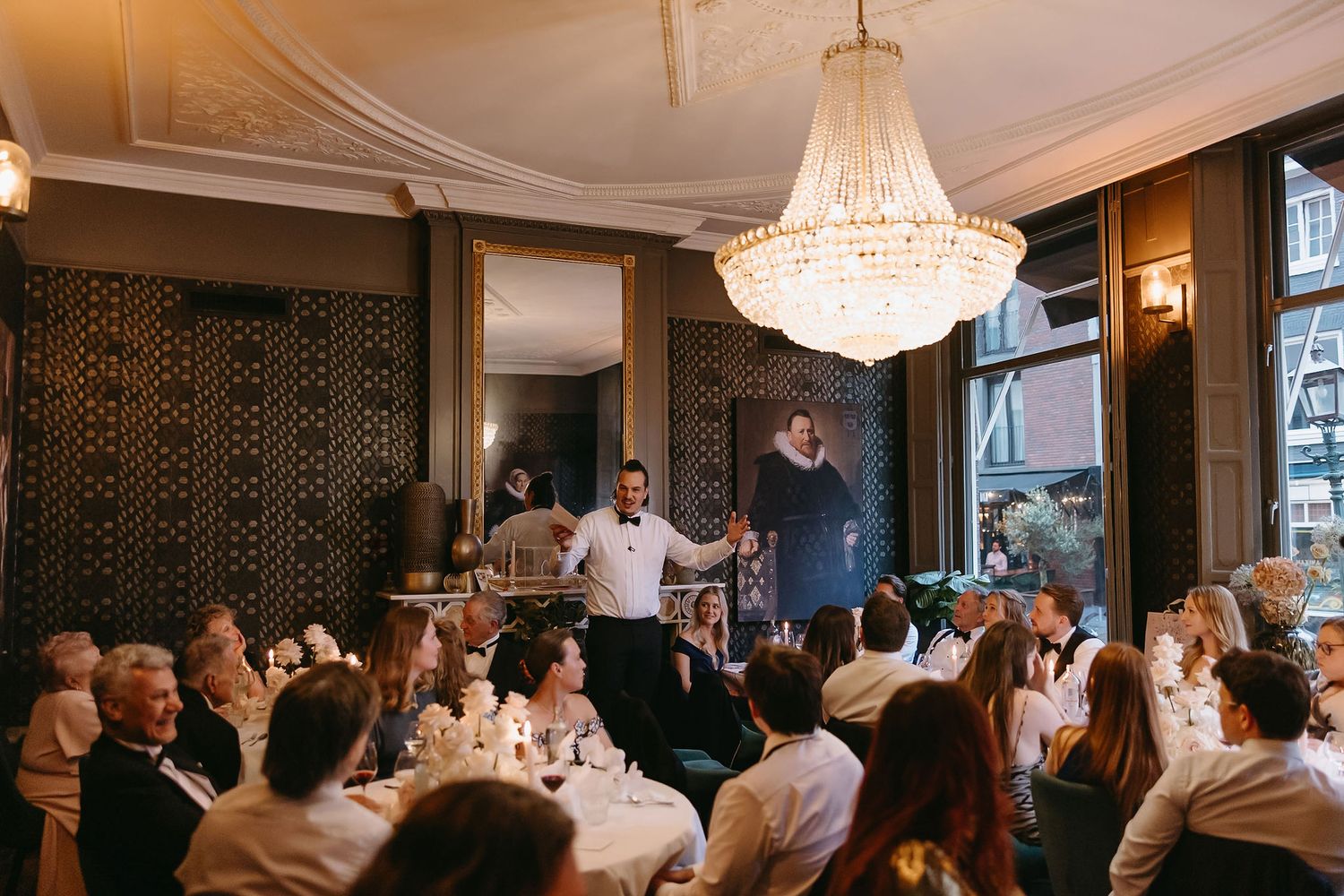 Elegant dining room with crystal chandelier and guests gathered for a formal celebration.