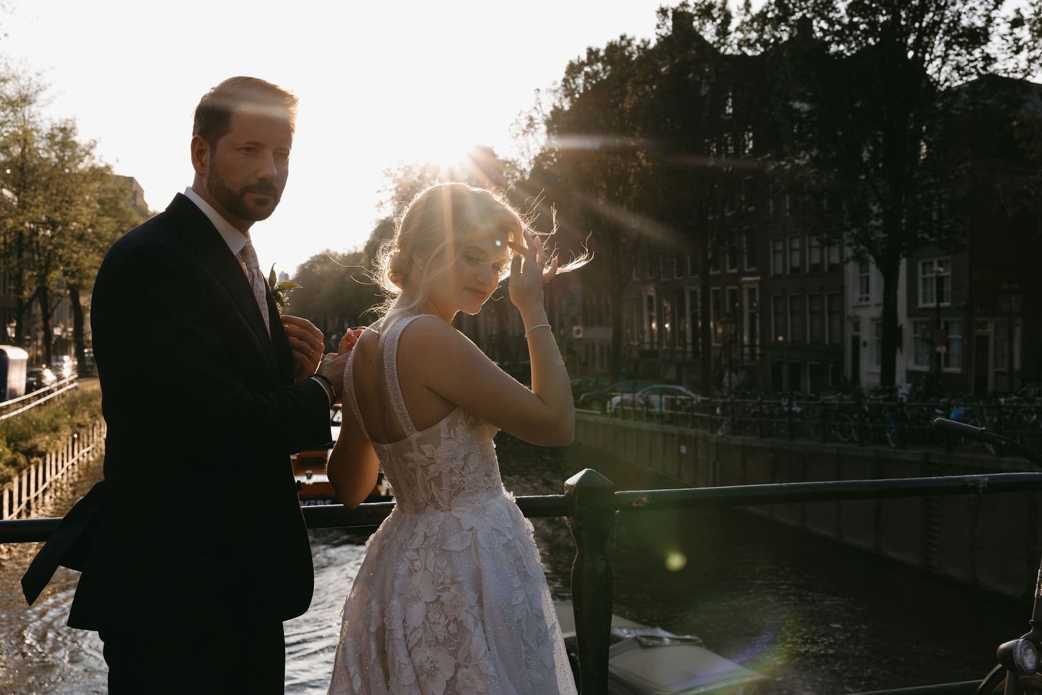 Newlyweds share an intimate moment at sunset along a canal in Amsterdam.