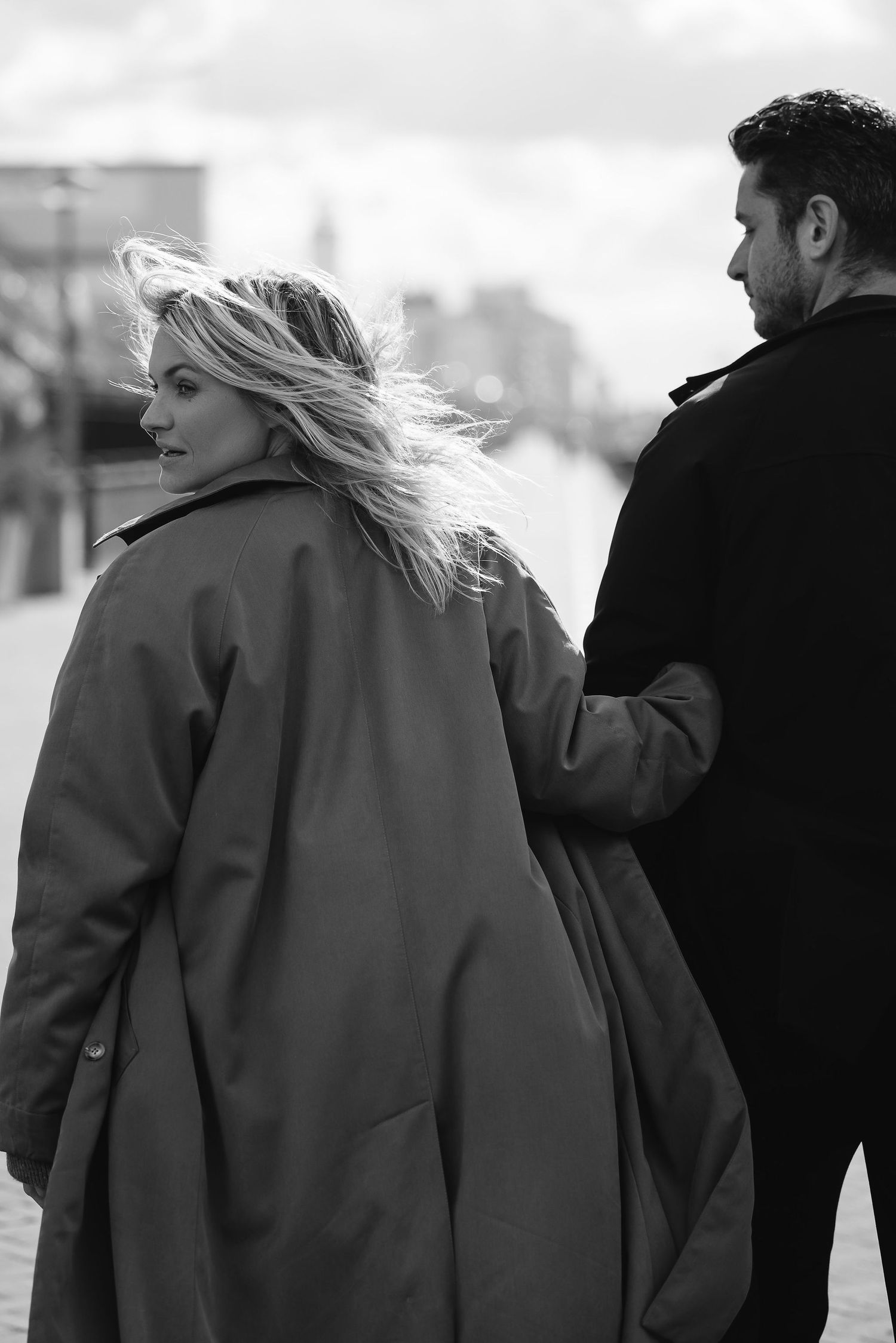 Romantic black and white photo of couple walking together in winter coats.