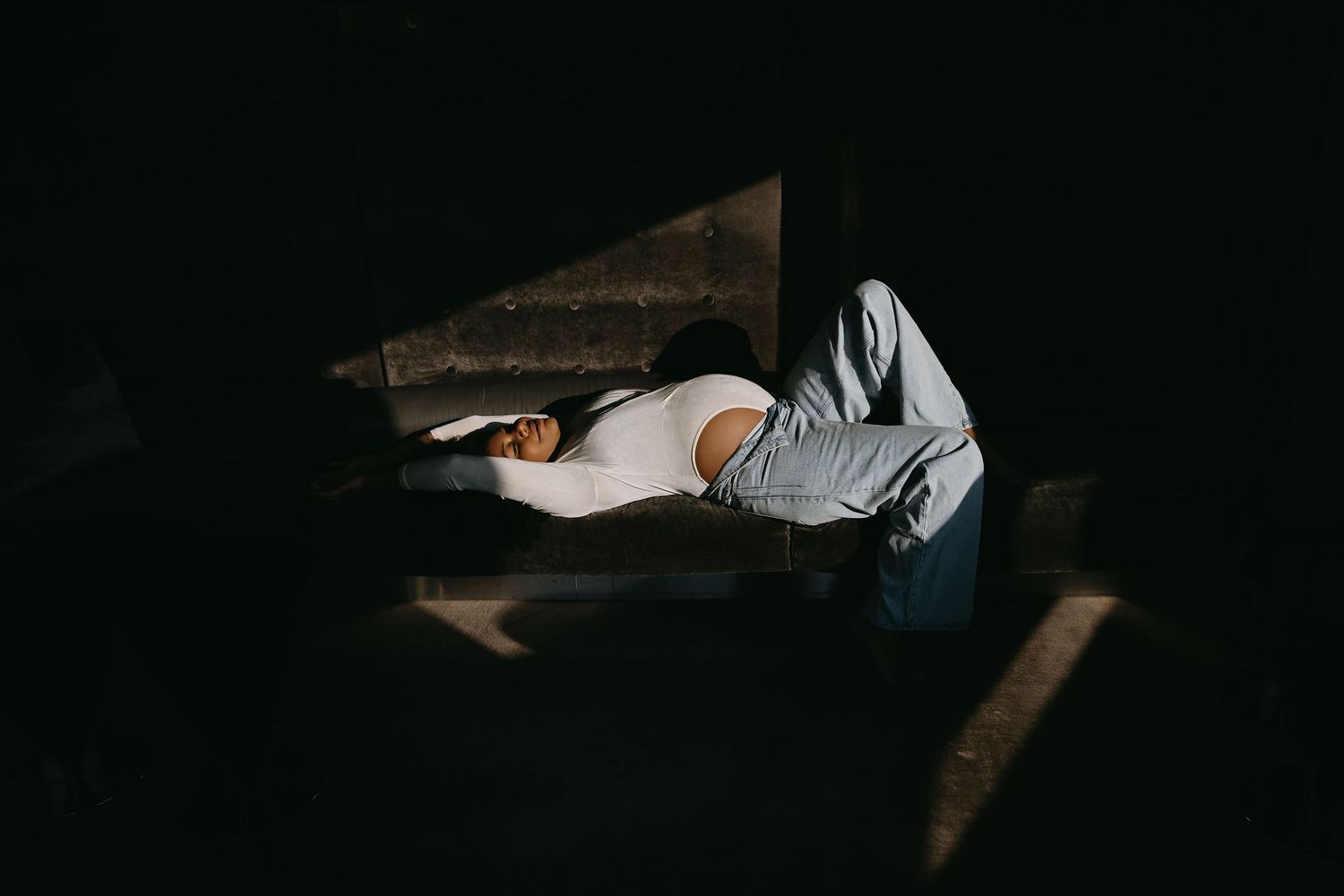 Minimalist photograph of a figure resting in deep shadows.