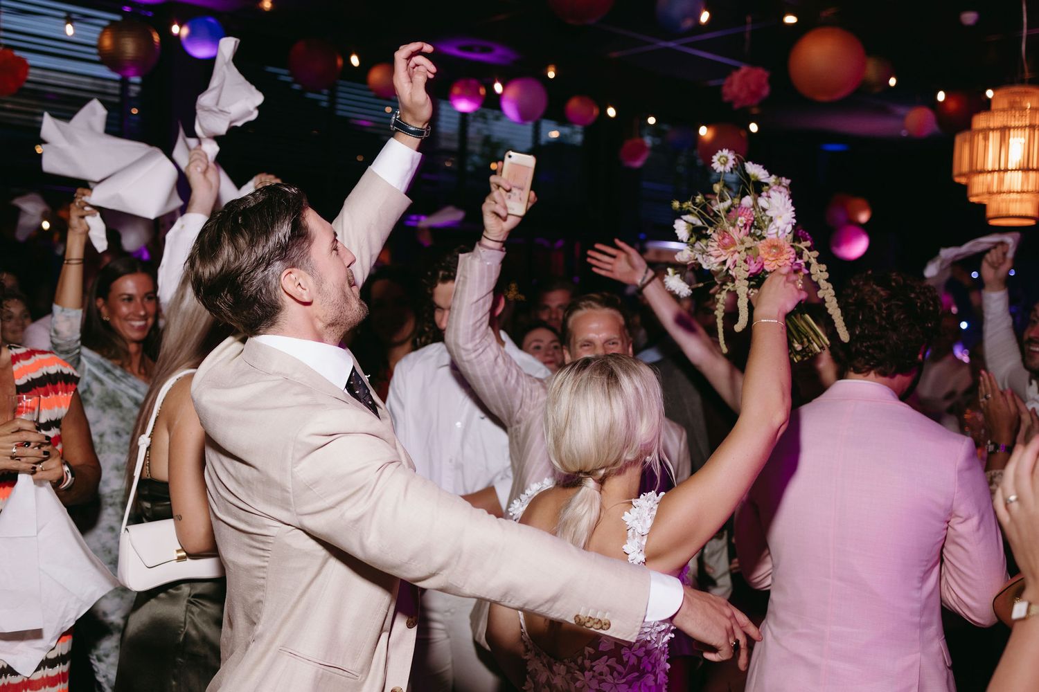 Wedding reception dance party with colorful lighting and energetic atmosphere.