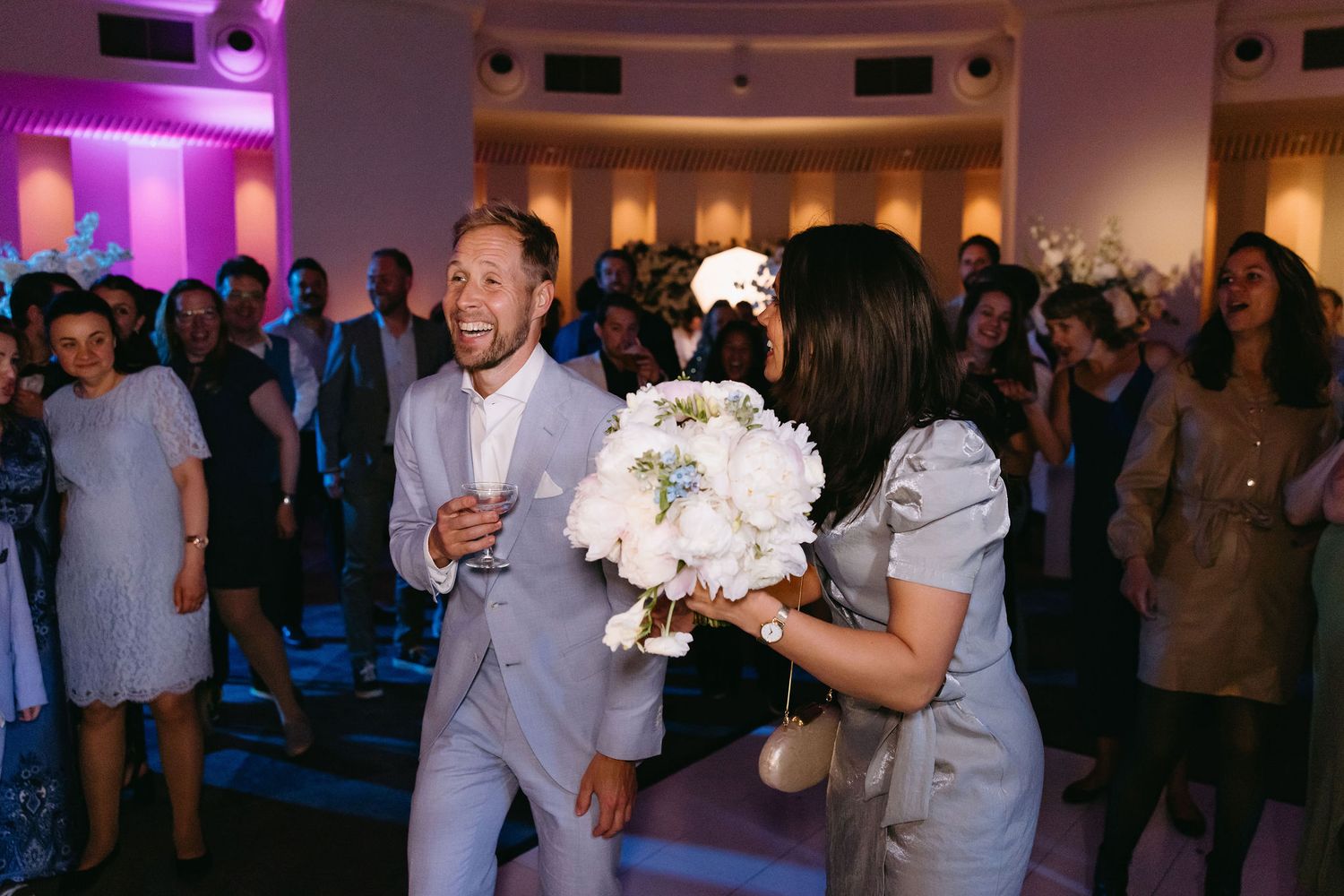 Wedding reception party scene with purple ambient lighting and dancing guests.
