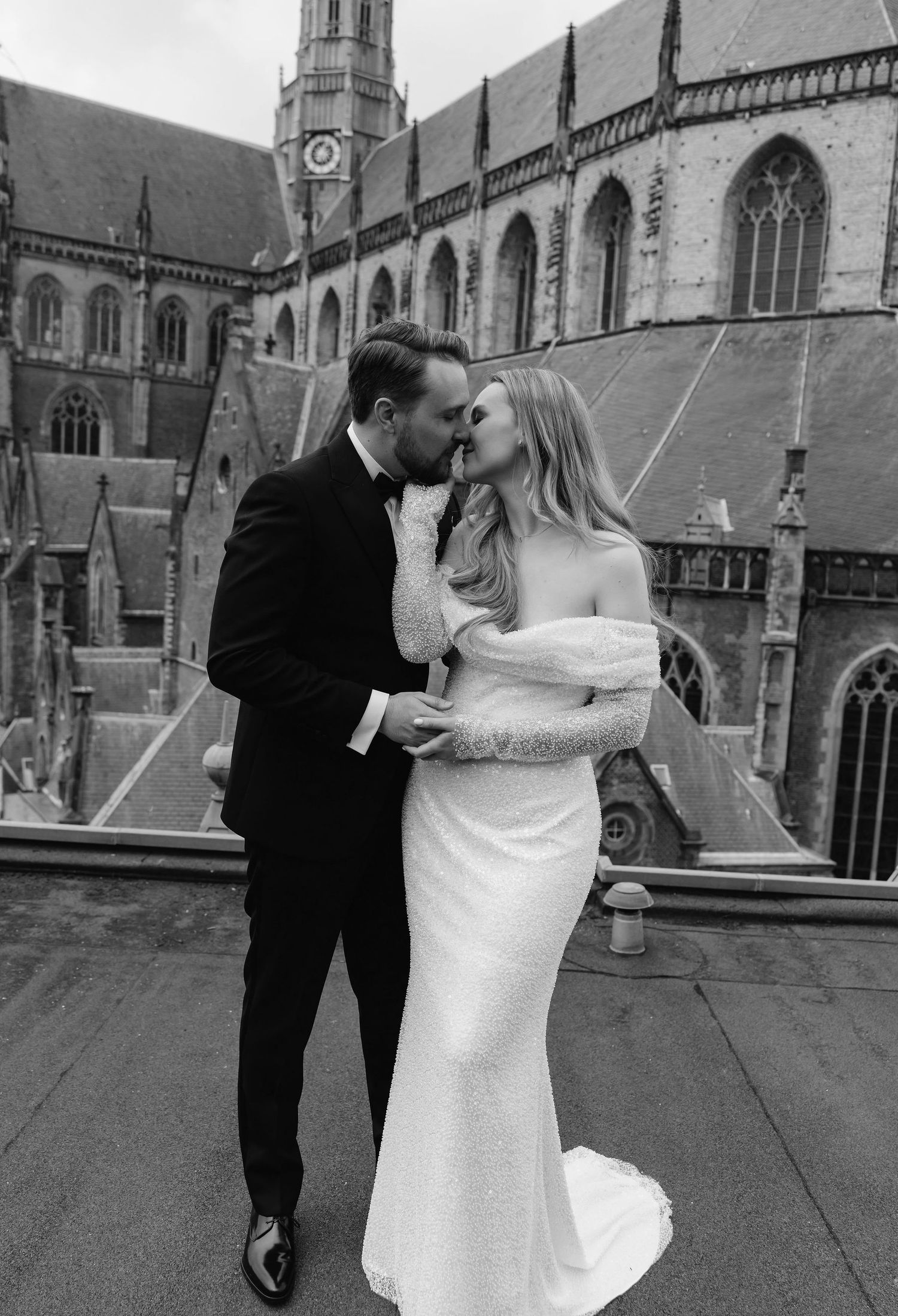 Romantic wedding portrait against a gothic cathedral backdrop in black and white.