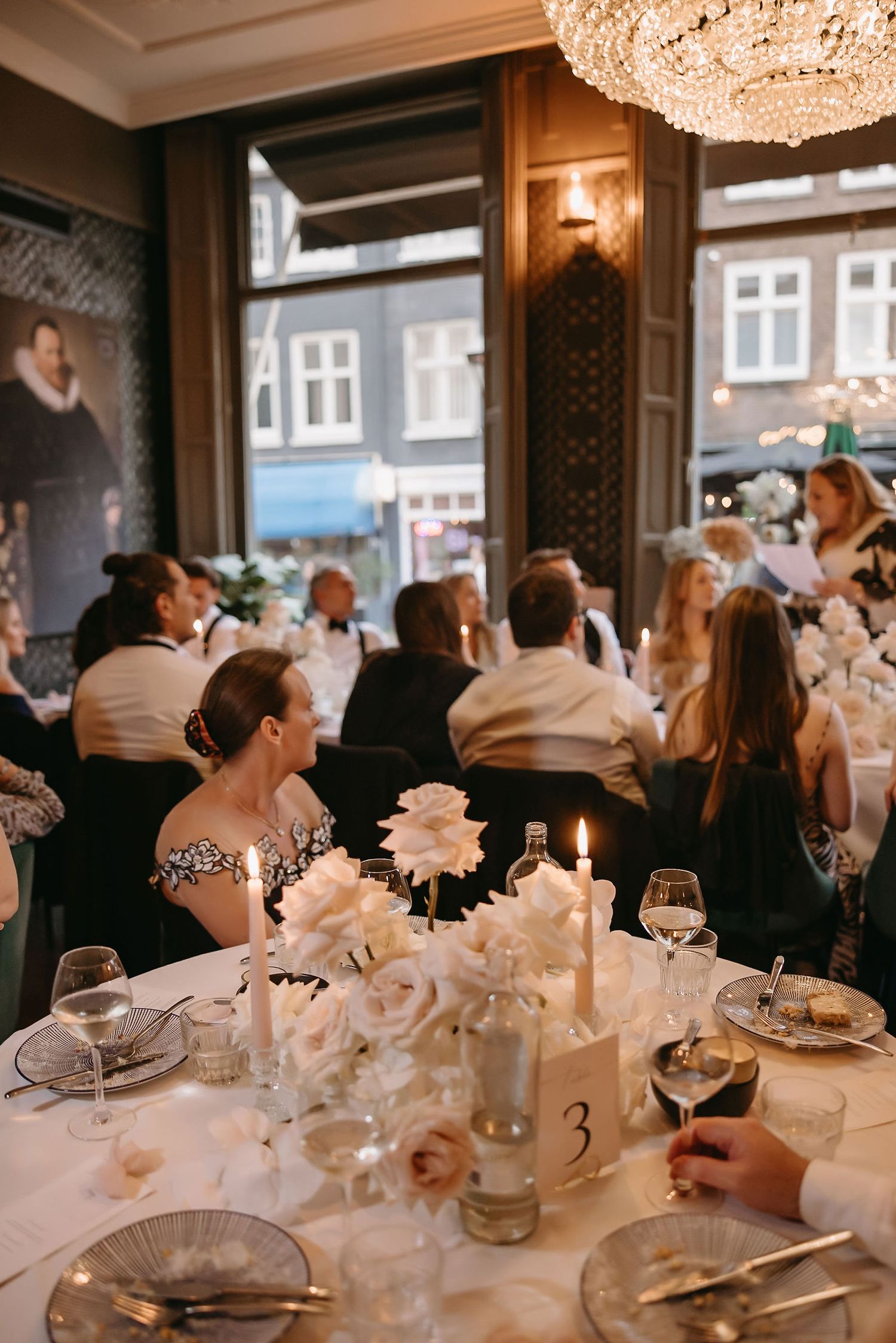 An elegant wedding reception table with crystal chandelier and floral centerpieces.