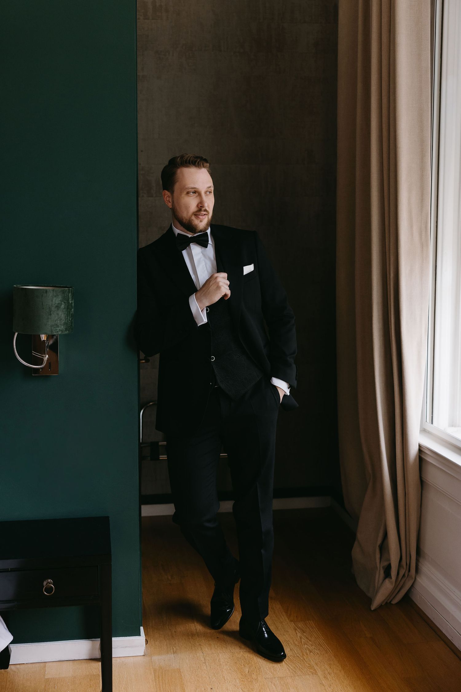 Artistic black and white photos of a groom in formal attire positioned in an elegant interior space.