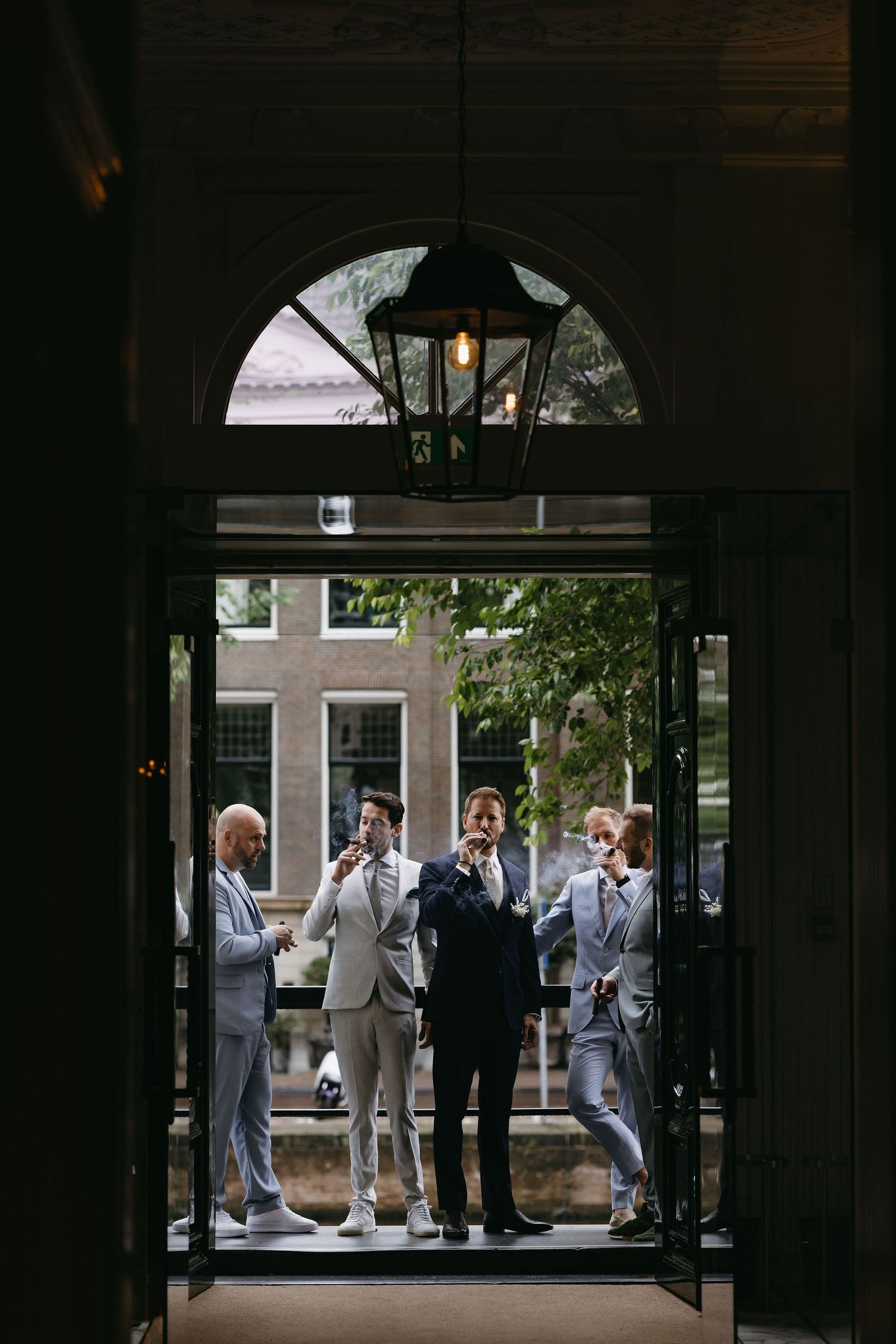 Silhouetted figures in formal attire gathered in a building entrance.
