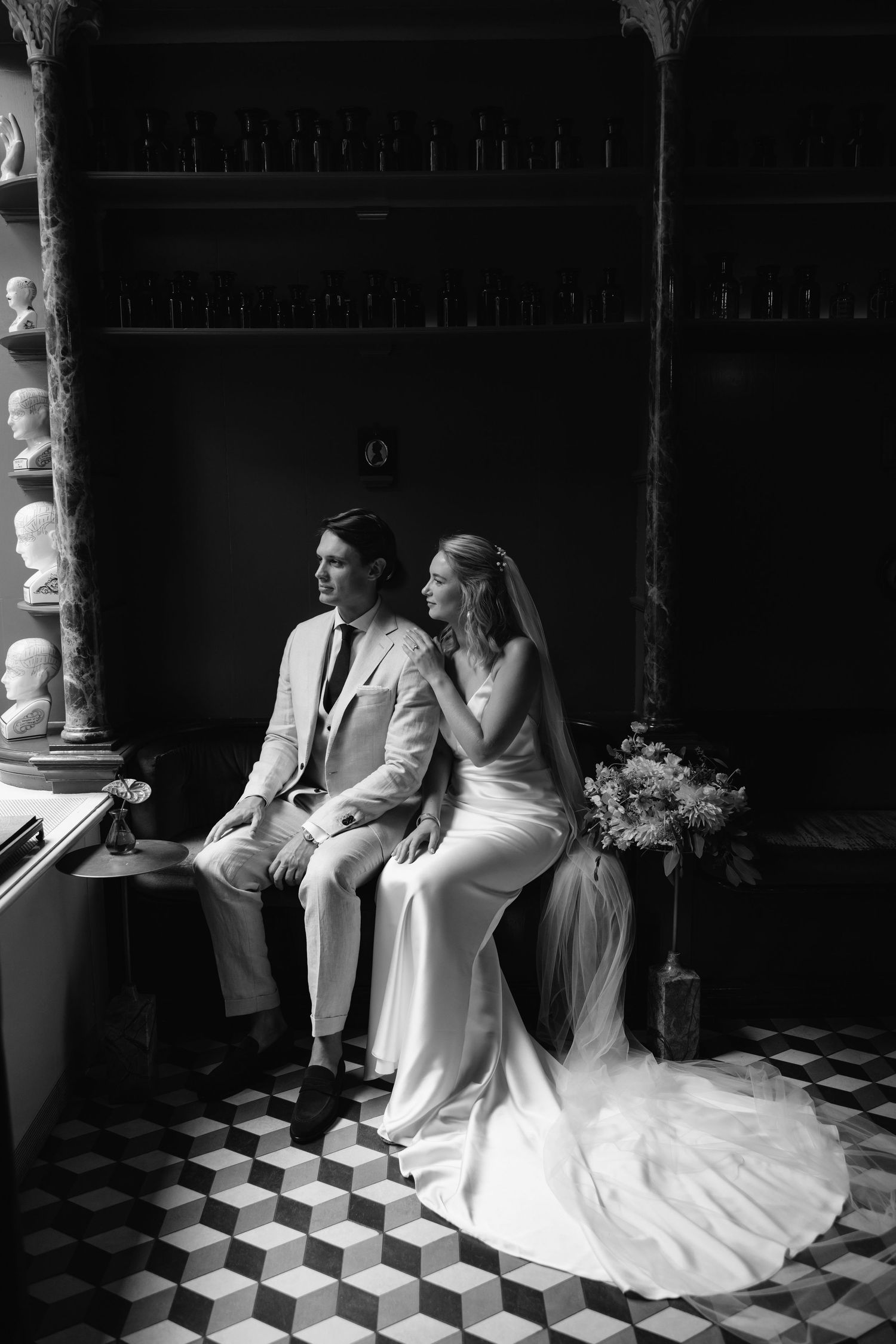 Black and white series of elegant wedding poses on a checkered floor in dramatic lighting.