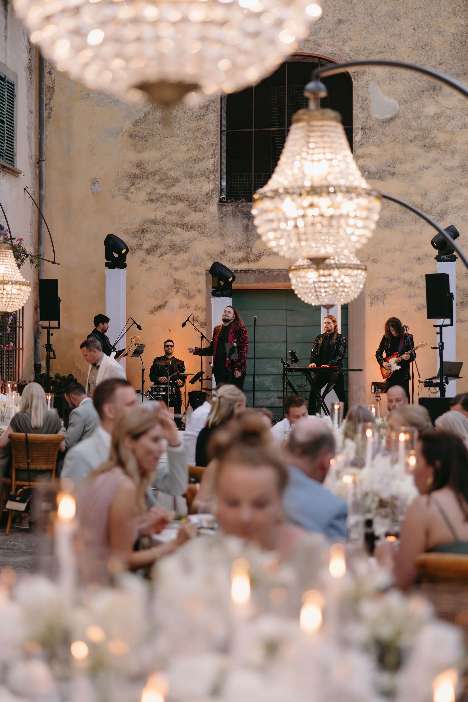Elegant reception with crystal chandeliers and live band performing for dining guests.