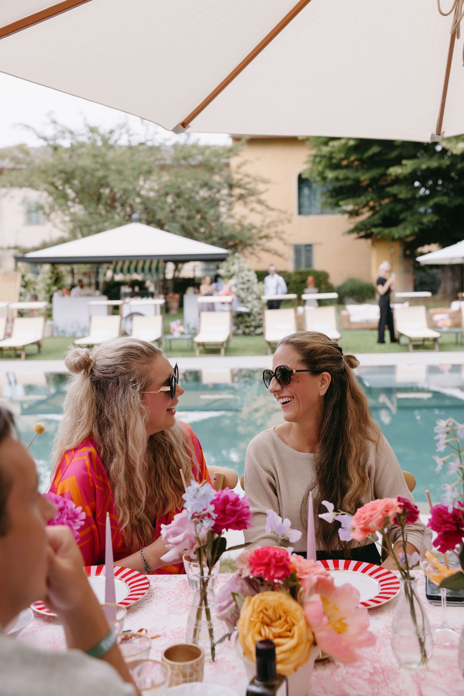 Poolside garden party with colorful flowers and white umbrellas at a luxury venue.