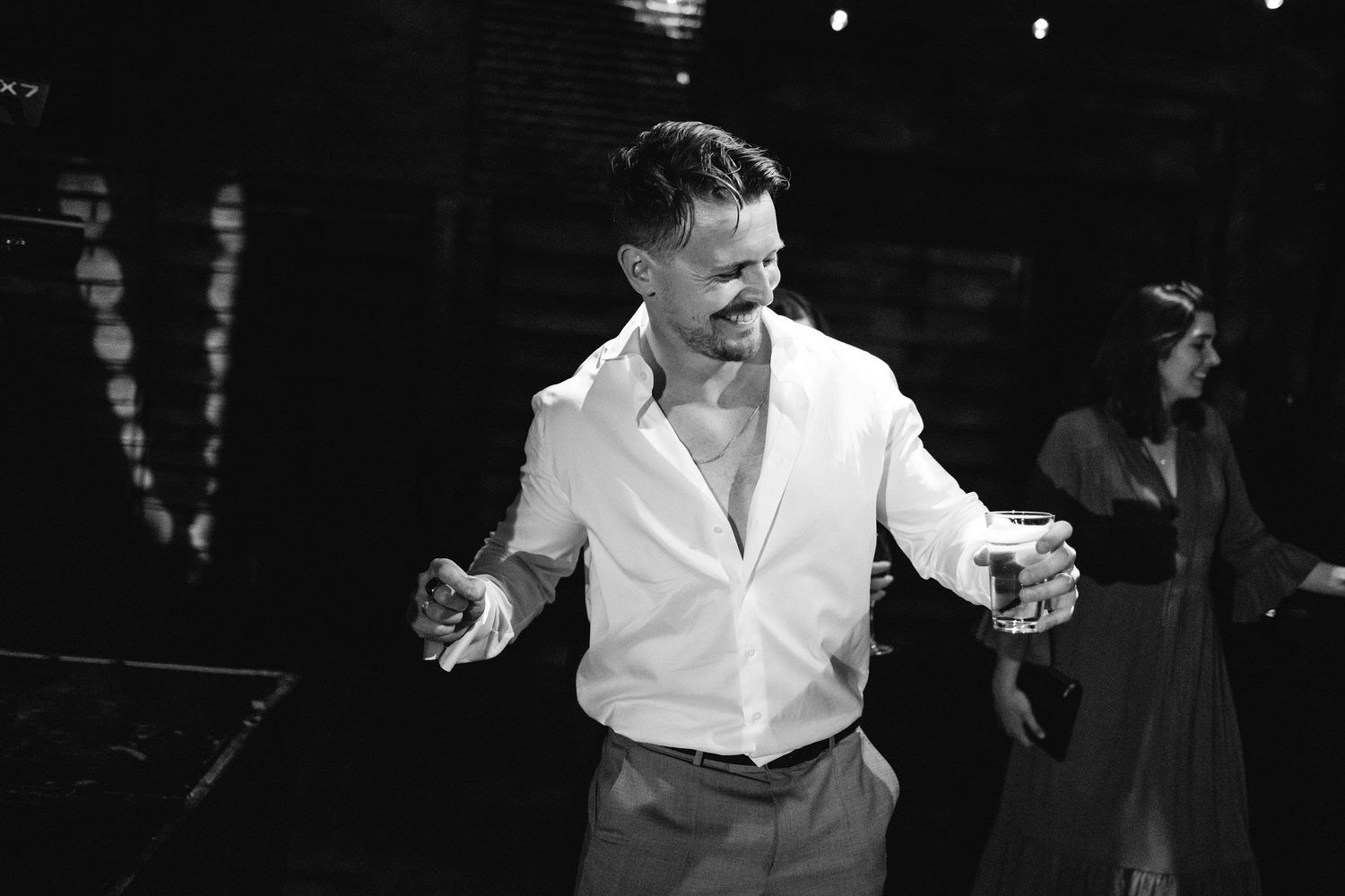 Black and white photo of someone dancing energetically at a celebration.