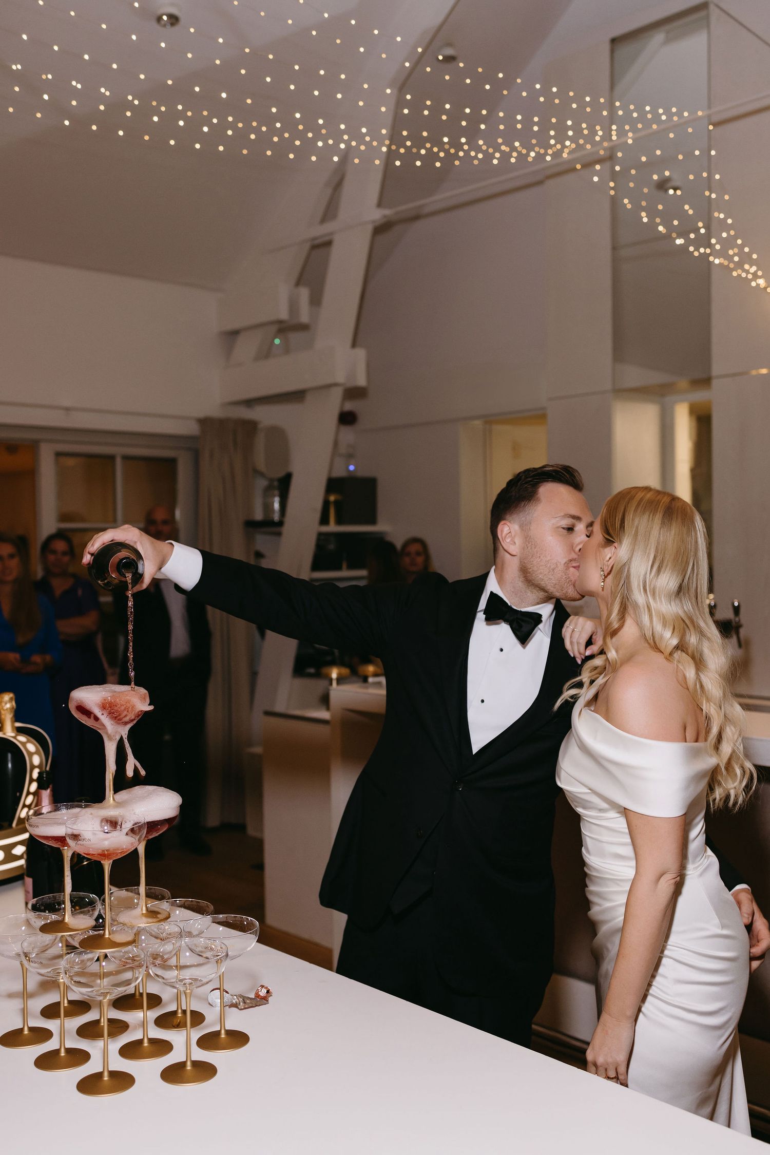 Couple sharing romantic moment at champagne tower during wedding reception.