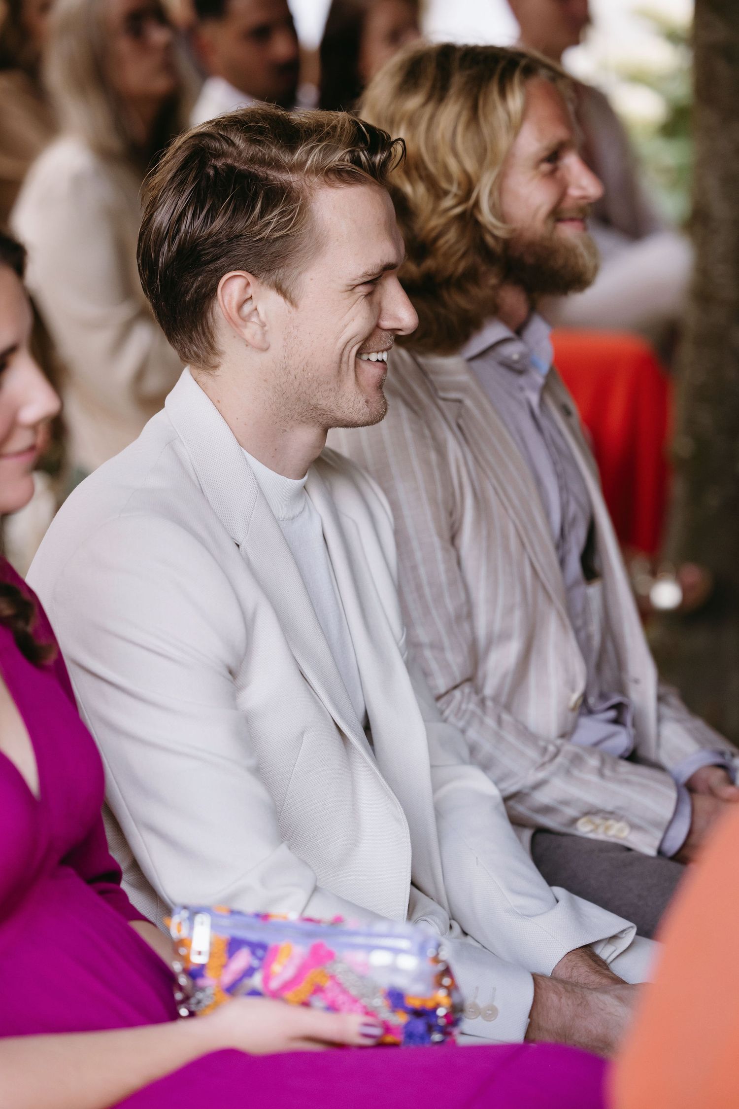 Wedding guests in formal attire seated during an outdoor celebration.