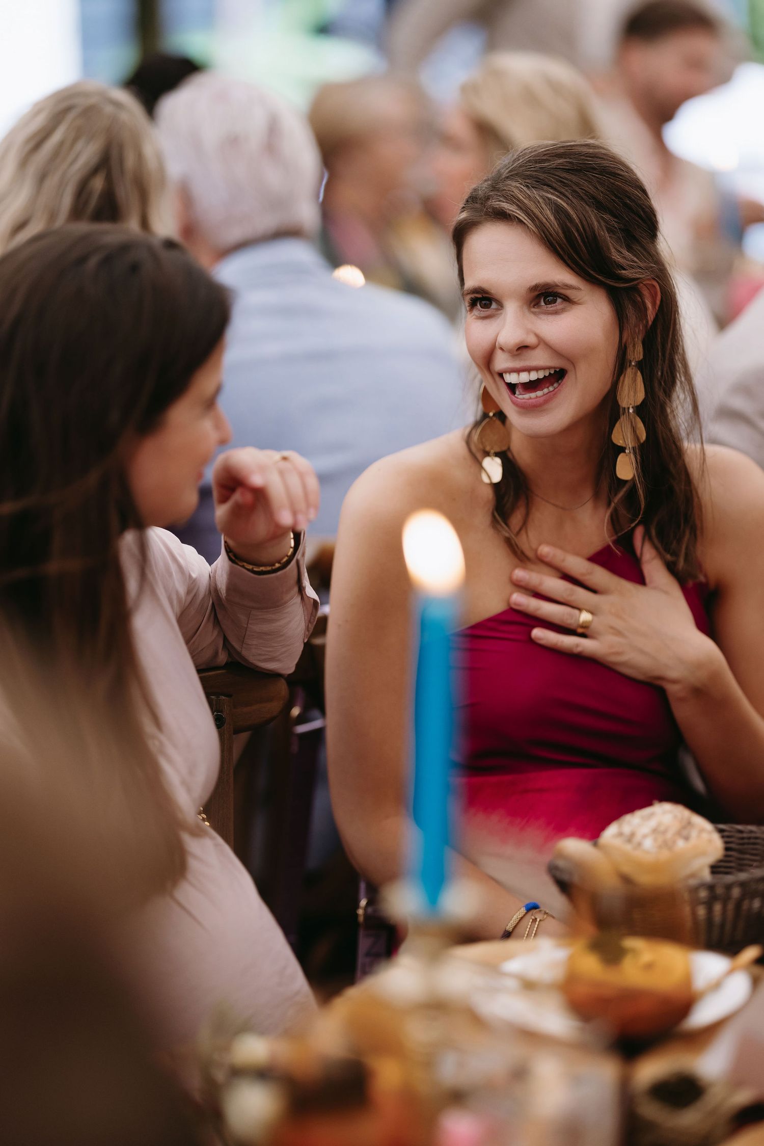 Guest in red dress enjoying conversation at wedding reception dinner.