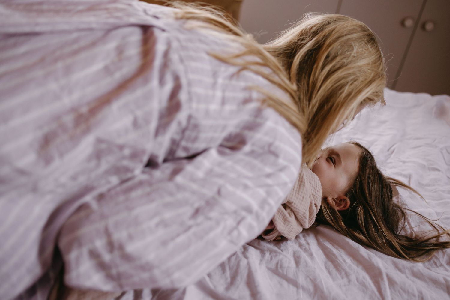 Soft pink tones highlight peaceful moments in bed with natural morning light.