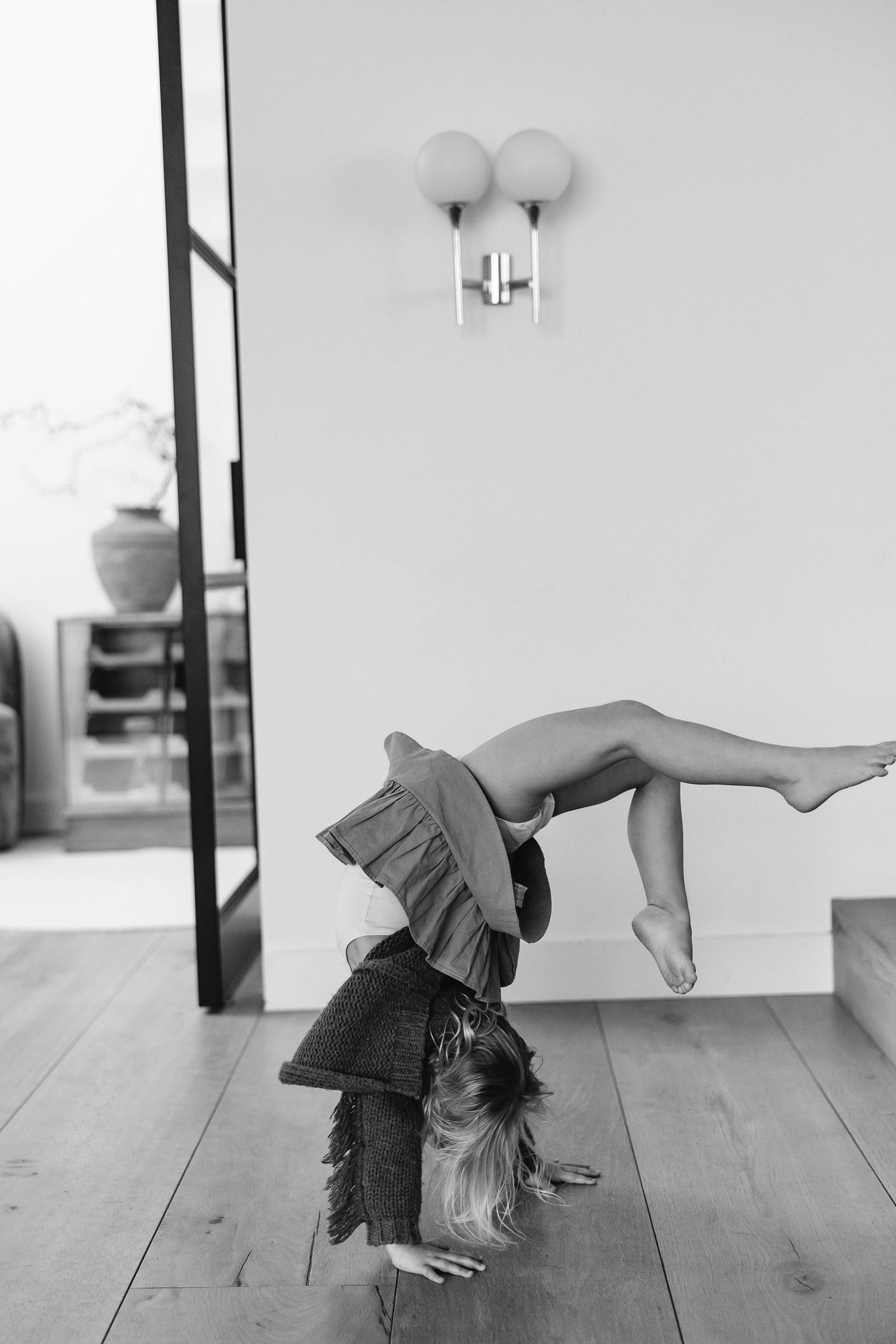 Young gymnast performs a graceful backbend on hardwood floor in black and white.