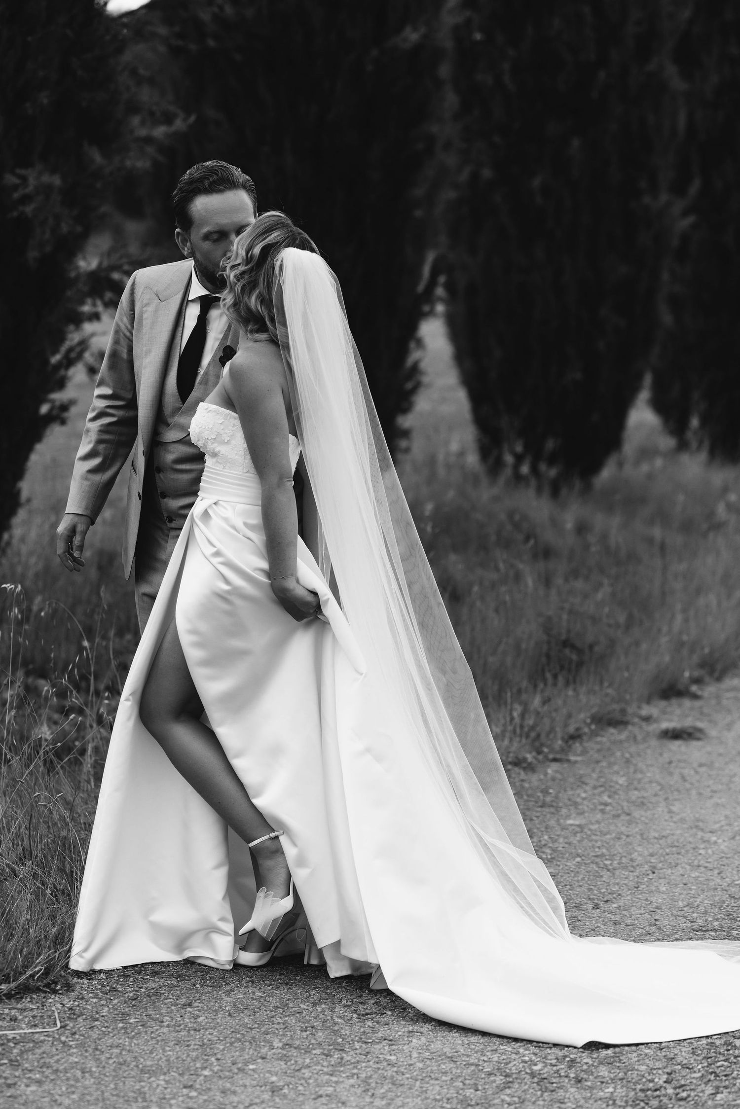 A dramatic black and white wedding portrait on a countryside path.